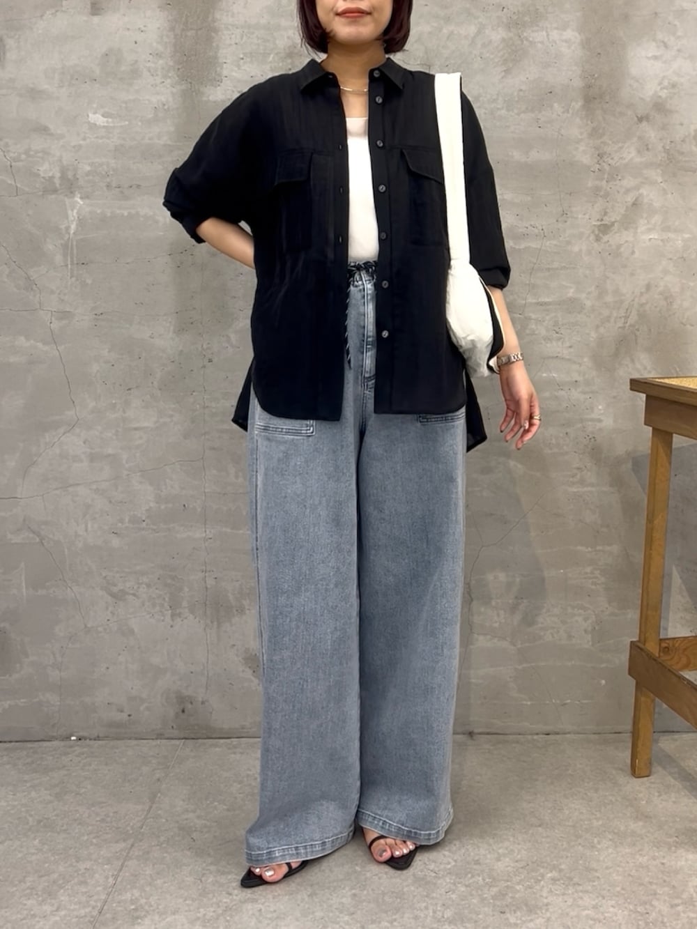 ブルー系のデニムパンツ、ブラック系のシャツ/ブラウス、ブラック系のショルダーバッグを着用したレディースの夏コーディネートの2枚目の写真