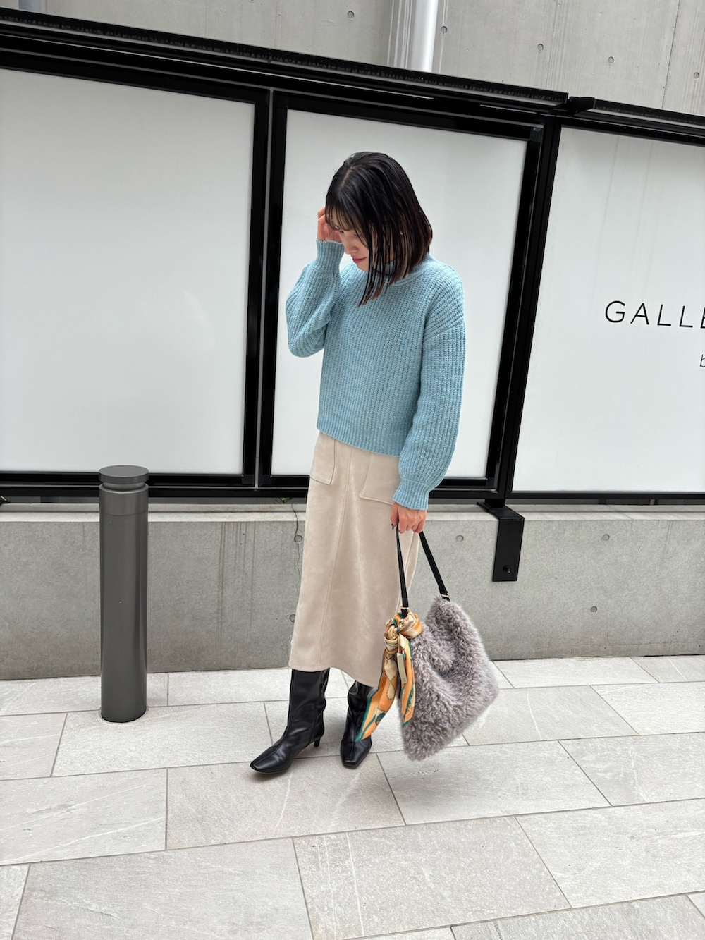 ブルー系のニット/セーター、ベージュ系のスカートを着用したレディースの秋コーディネートの4枚目の写真