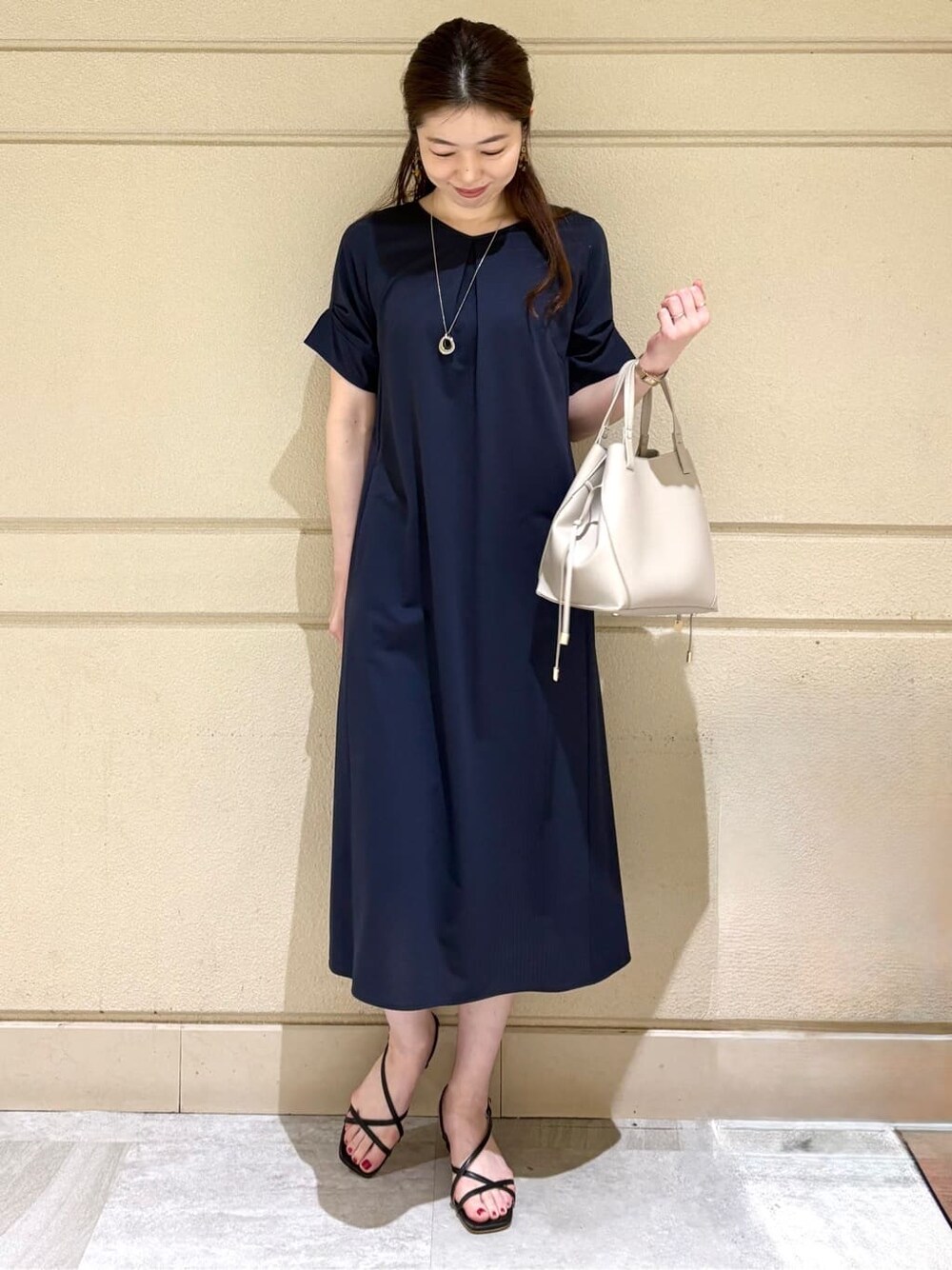 ブルー系のワンピース、グレー系のトートバッグ、シルバー系のネックレスを着用したレディースの夏コーディネートの2枚目の写真