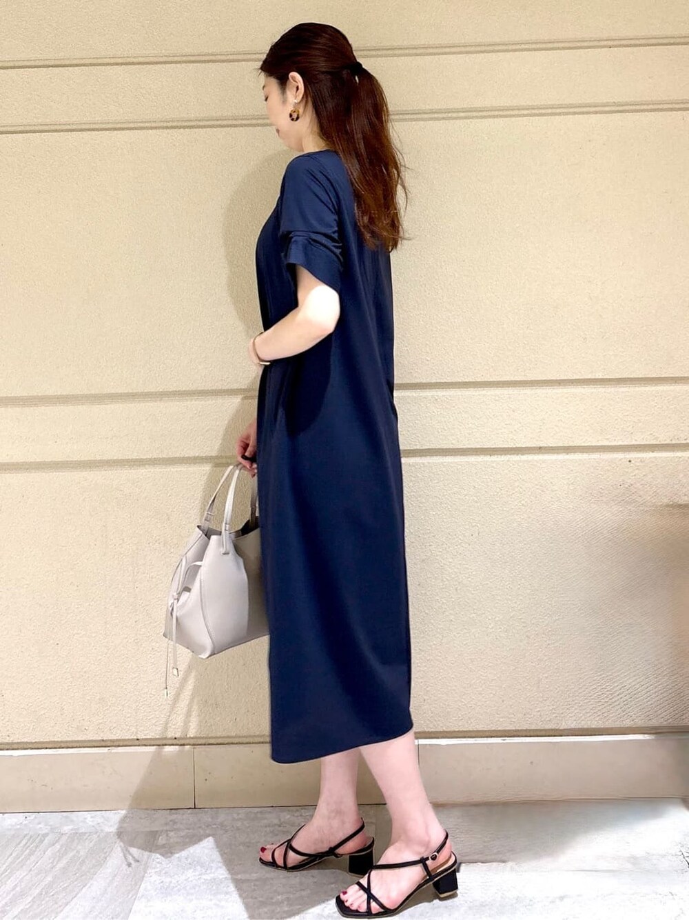 ブルー系のワンピース、グレー系のトートバッグ、シルバー系のネックレスを着用したレディースの夏コーディネートの3枚目の写真