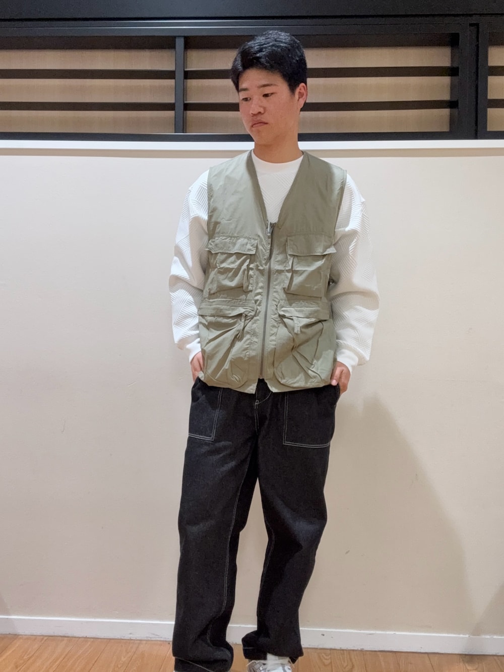 グリーン系のベスト、ホワイト系のTシャツ/カットソー、ブラック系のデニムパンツを着用したメンズの春コーディネートの2枚目の写真