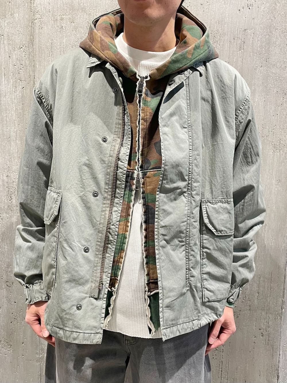 グリーン系のミリタリージャケット、グレー系のデニムパンツ、ホワイト系のTシャツ/カットソーを着用したメンズの冬コーディネートの2枚目の写真