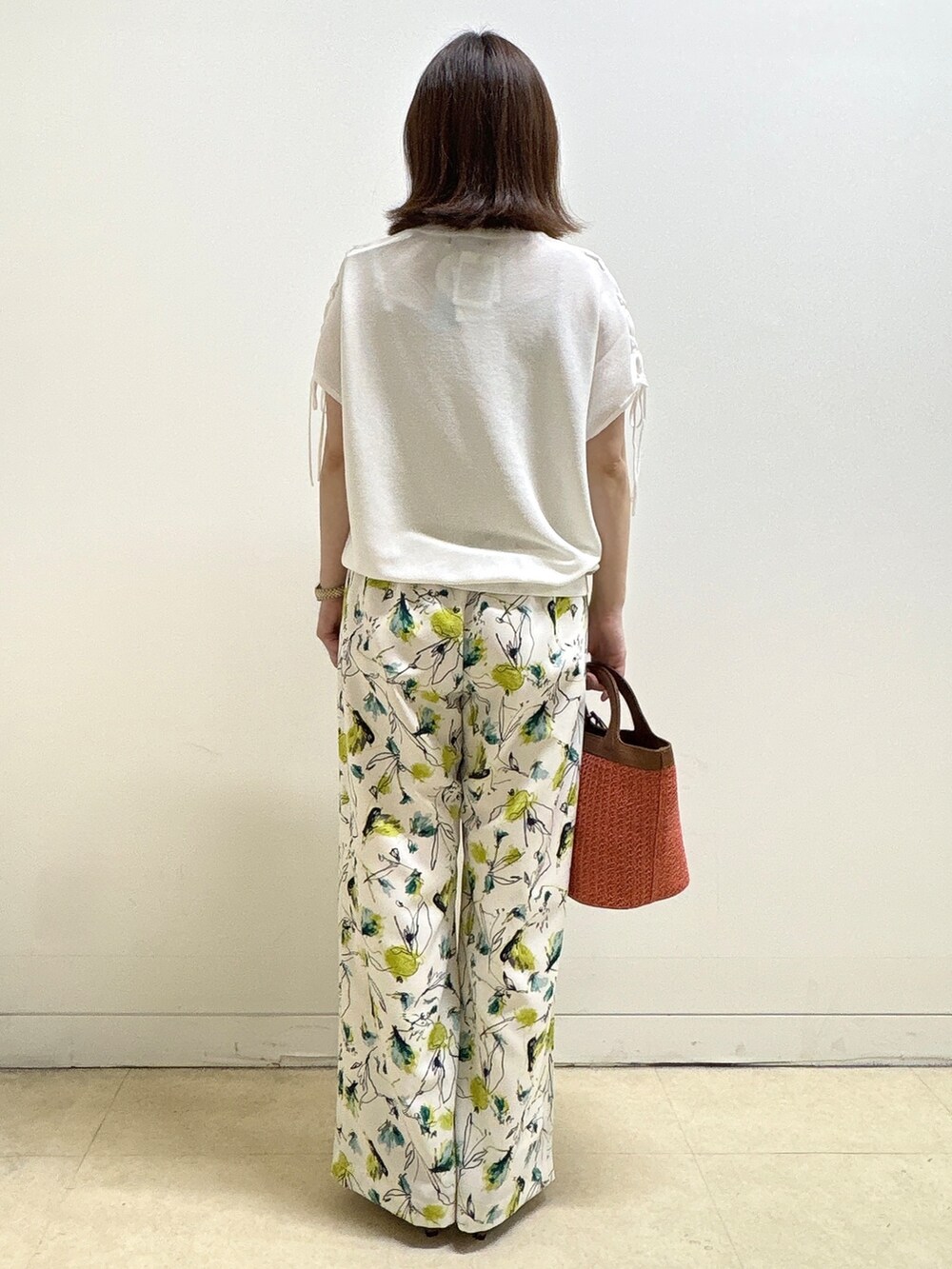 ホワイト系のニット/セーター、ベージュ系のその他パンツ、オレンジ系のショルダーバッグを着用したレディースの夏コーディネートの6枚目の写真