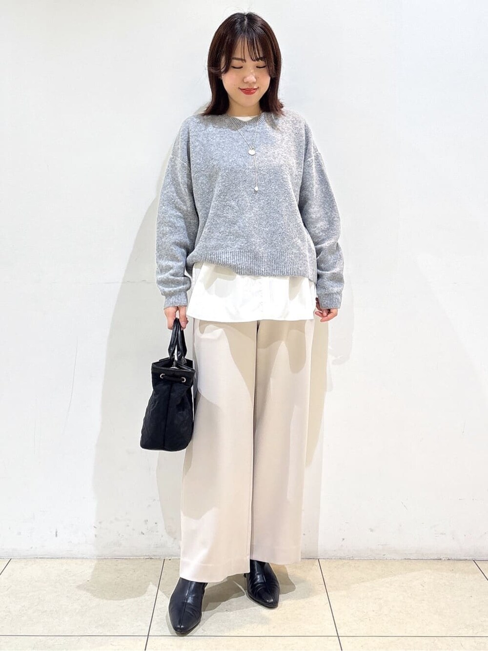 グレー系のニット/セーター、ホワイト系のTシャツ/カットソー、ベージュ系のその他パンツを着用したレディースの冬コーディネートの3枚目の写真