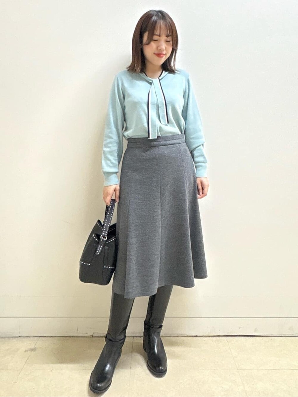 グレー系のダウンジャケット/コート、ブルー系のニット/セーター、グレー系のスカートを着用したレディースの秋コーディネートの7枚目の写真