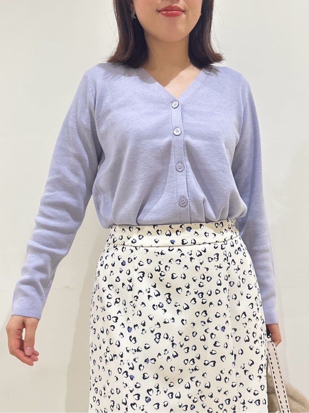 パープル系のカーディガン/ボレロ、ベージュ系のスカート、ベージュ系のハンドバッグを着用したレディースの冬コーディネートの7枚目の写真