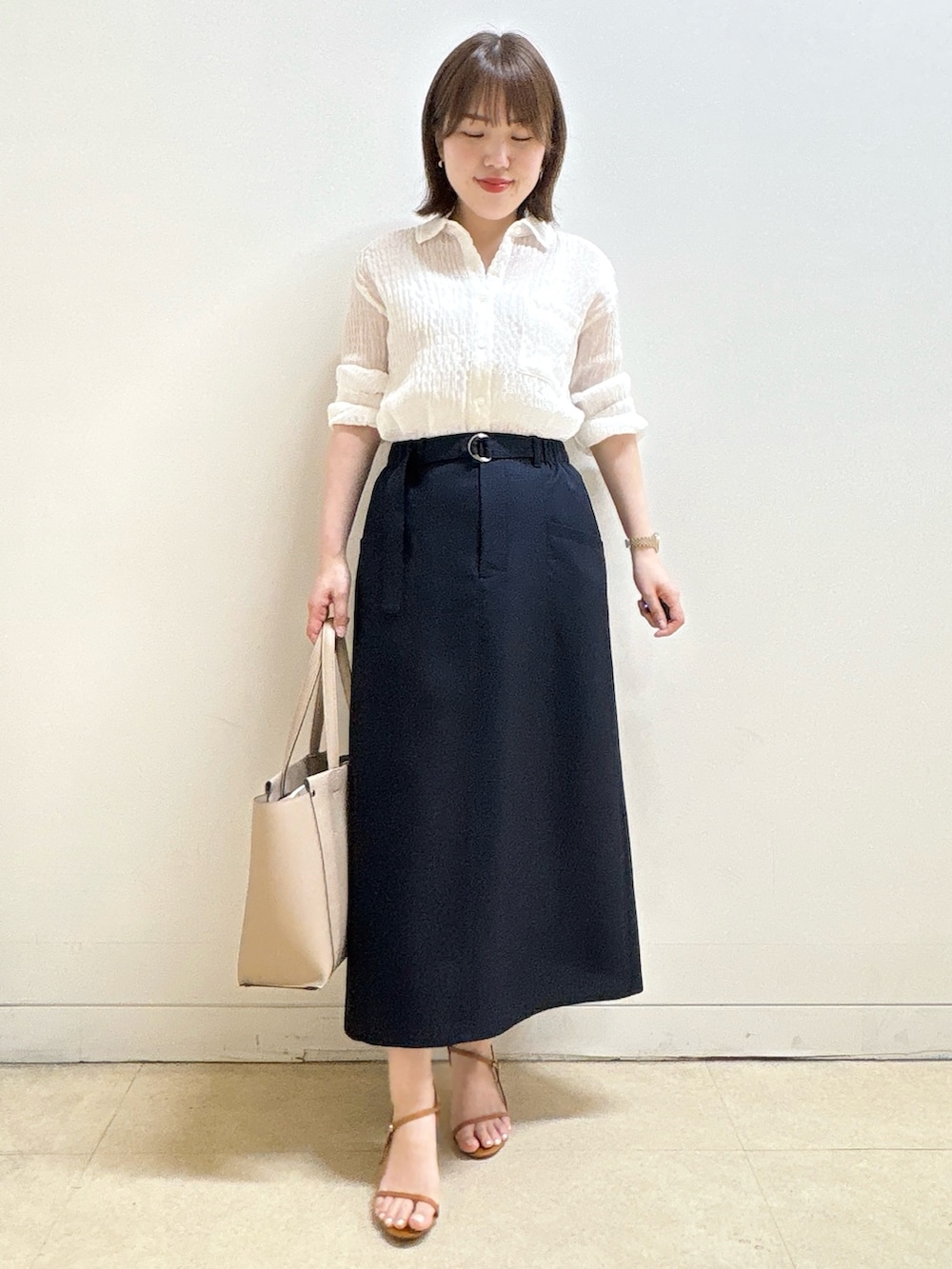 ホワイト系のシャツ/ブラウス、ブルー系のスカート、ベージュ系のトートバッグを着用したレディースの夏コーディネートの2枚目の写真