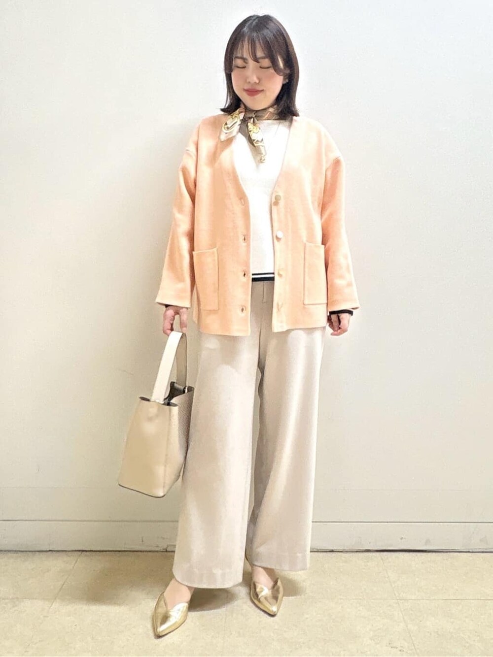ベージュ系のその他パンツ、ホワイト系のニット/セーター、オレンジ系のカーディガン/ボレロを着用したレディースの冬コーディネートの6枚目の写真