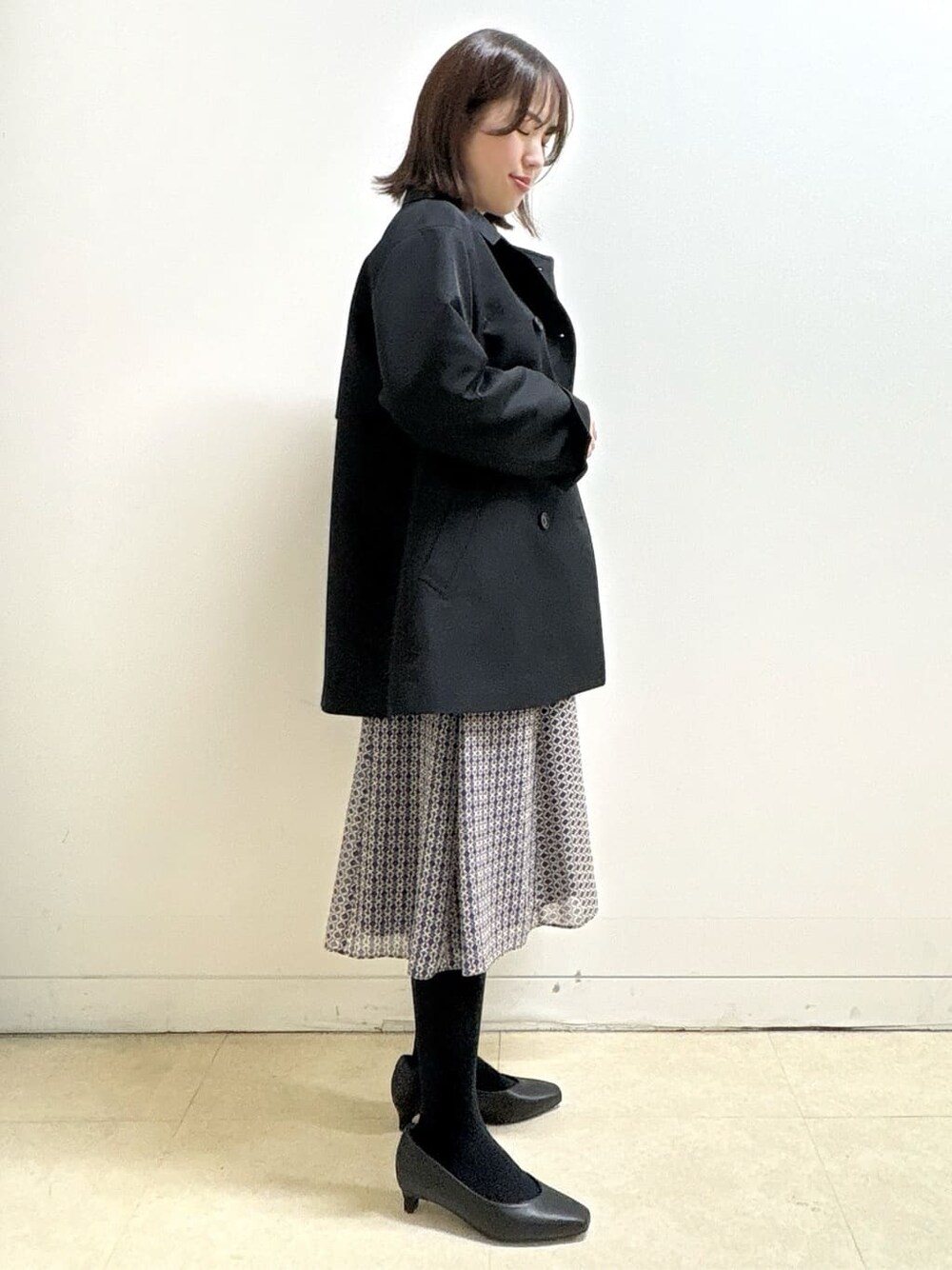 ブラック系のニット/セーター、ブルー系のスカート、ブラック系のパンプスを着用したレディースの冬コーディネートの8枚目の写真