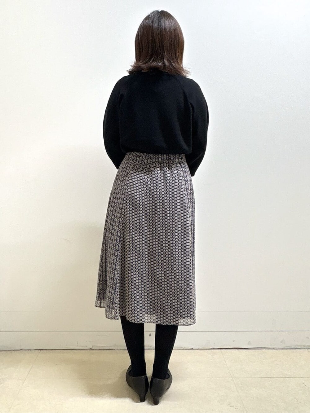 ブラック系のニット/セーター、ブルー系のスカート、ブラック系のパンプスを着用したレディースの冬コーディネートの6枚目の写真