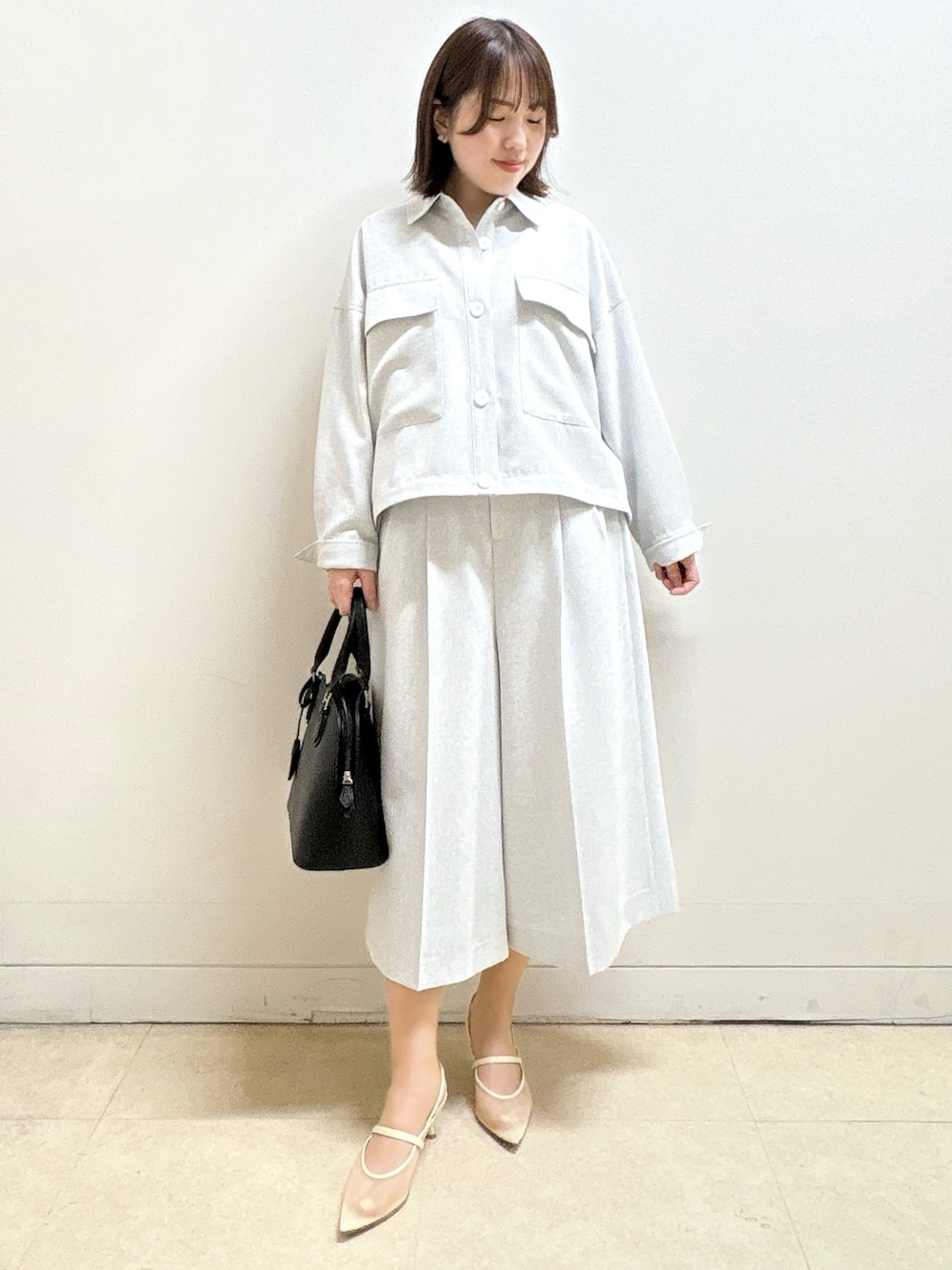 ブラック系のハンドバッグ、ホワイト系のTシャツ/カットソー、グレー系のブルゾンを着用したレディースの春コーディネートの4枚目の写真
