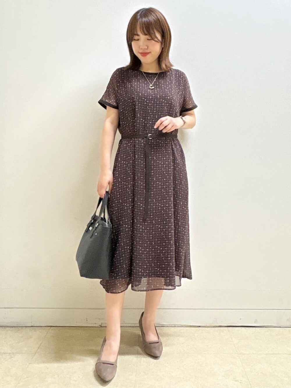 ブラウン系のワンピース、ベージュ系のパンプス、ブラック系のハンドバッグを着用したレディースの秋コーディネートの2枚目の写真