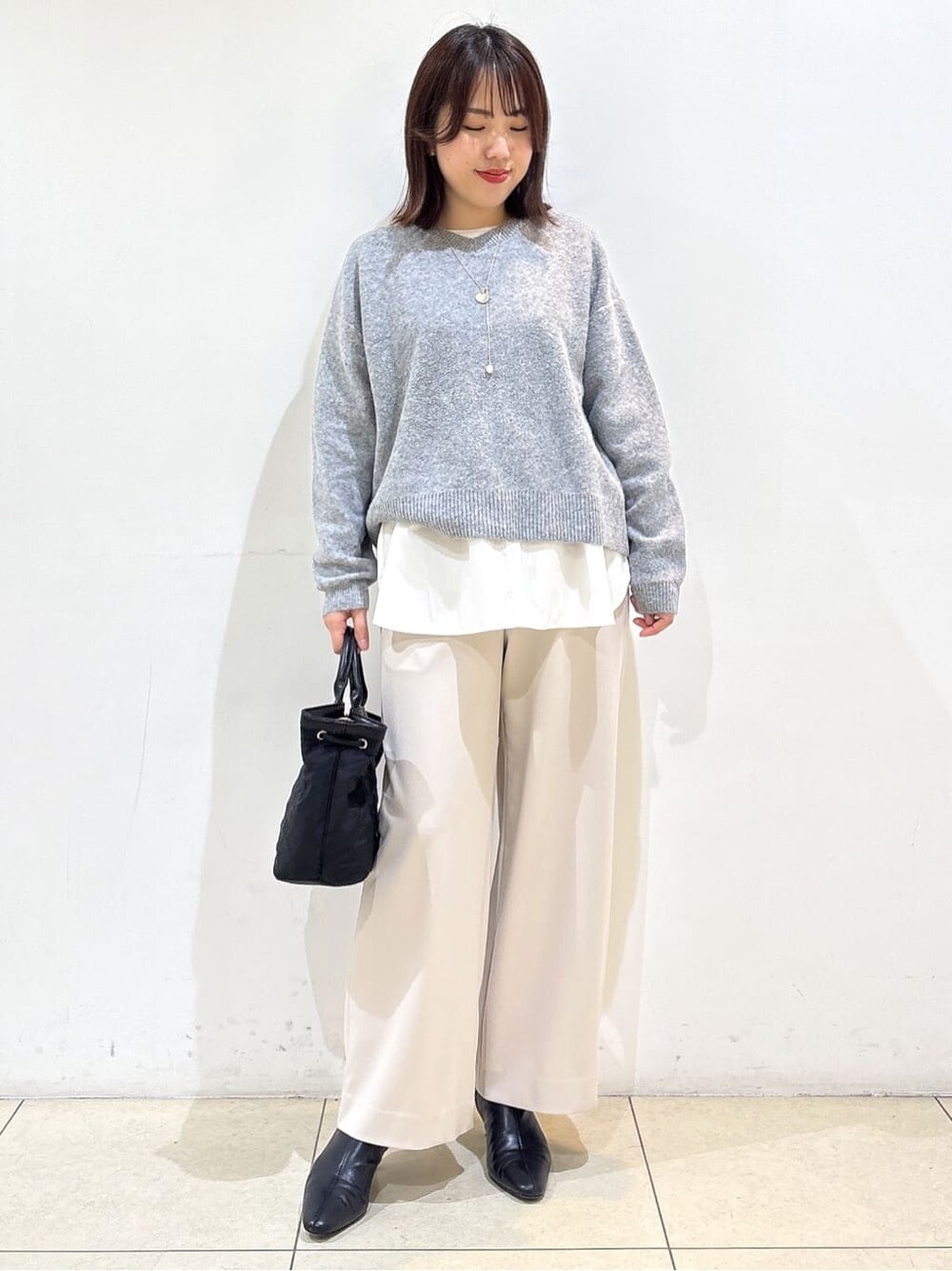グレー系のニット/セーター、ホワイト系のTシャツ/カットソー、ベージュ系のその他パンツを着用したレディースの冬コーディネートの2枚目の写真
