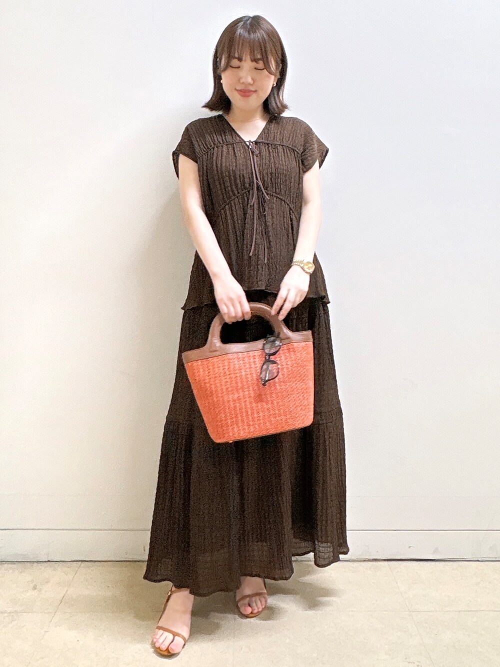 ブラウン系のシャツ/ブラウス、ブラウン系のスカート、オレンジ系のショルダーバッグを着用したレディースの夏コーディネートの5枚目の写真