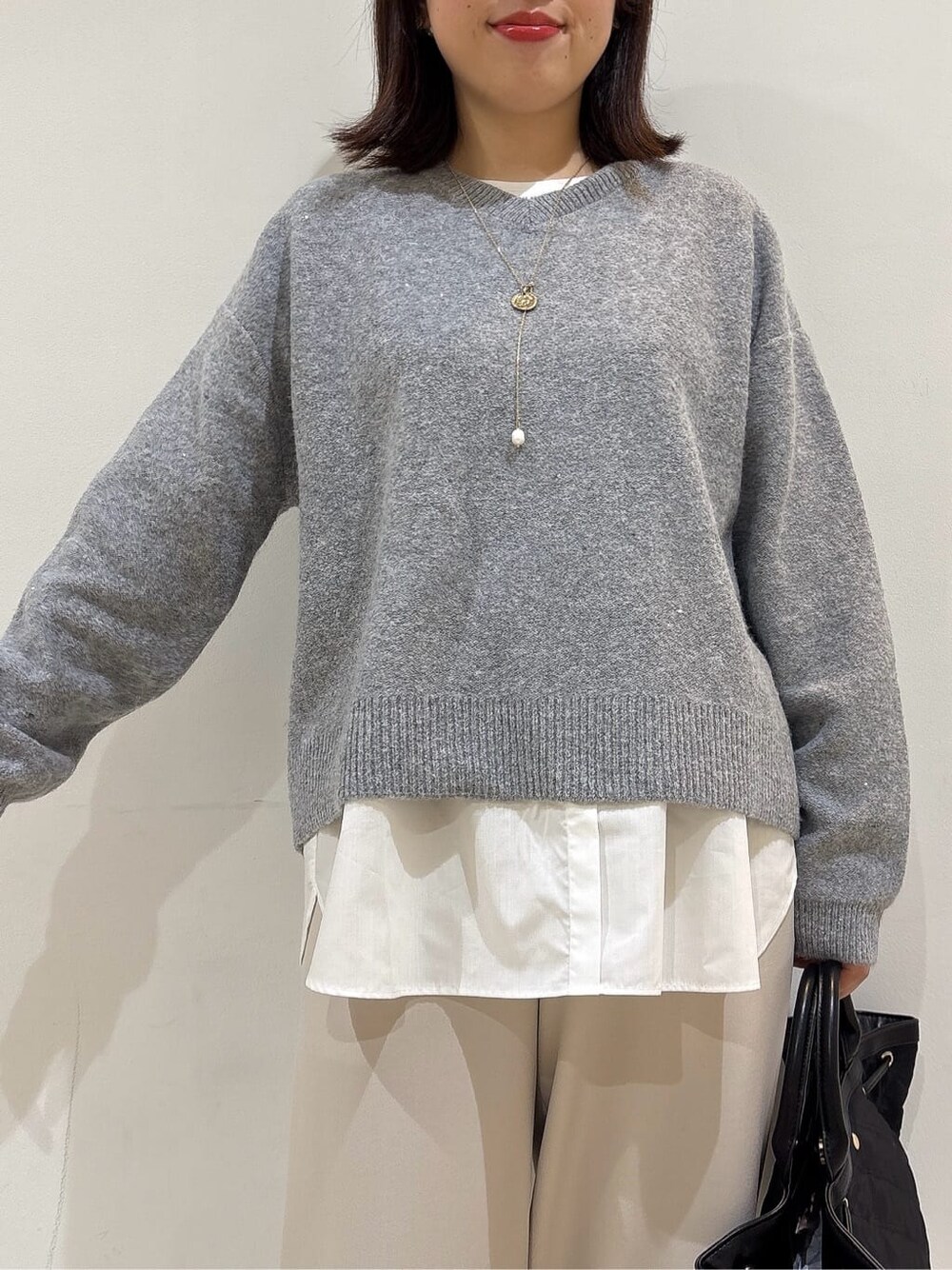 グレー系のニット/セーター、ホワイト系のTシャツ/カットソー、ベージュ系のその他パンツを着用したレディースの冬コーディネートの7枚目の写真
