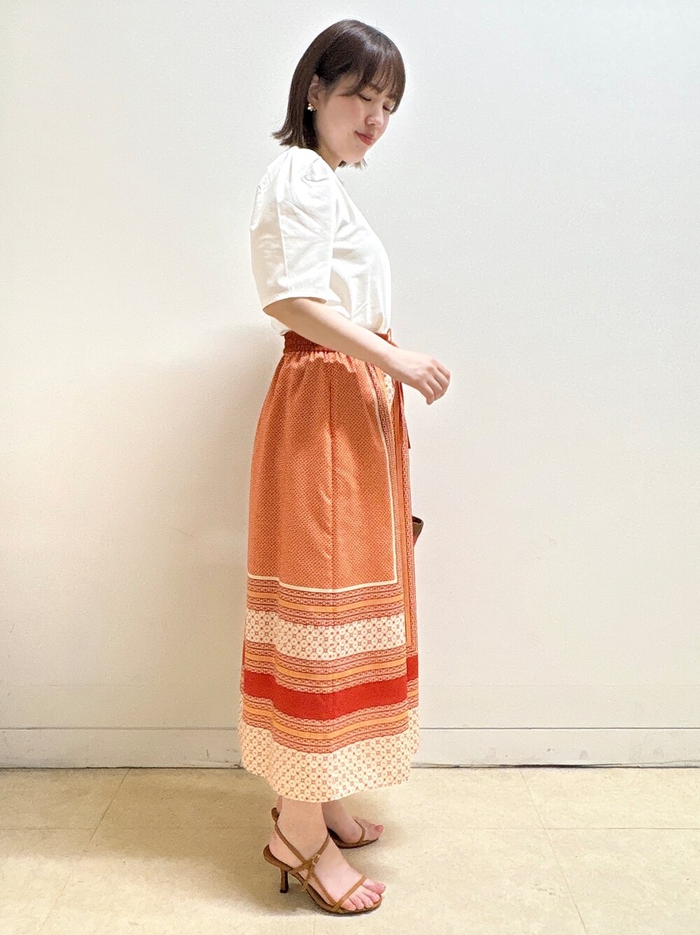 ホワイト系のTシャツ/カットソー、オレンジ系のスカート、オレンジ系のショルダーバッグを着用したレディースの夏コーディネートの5枚目の写真