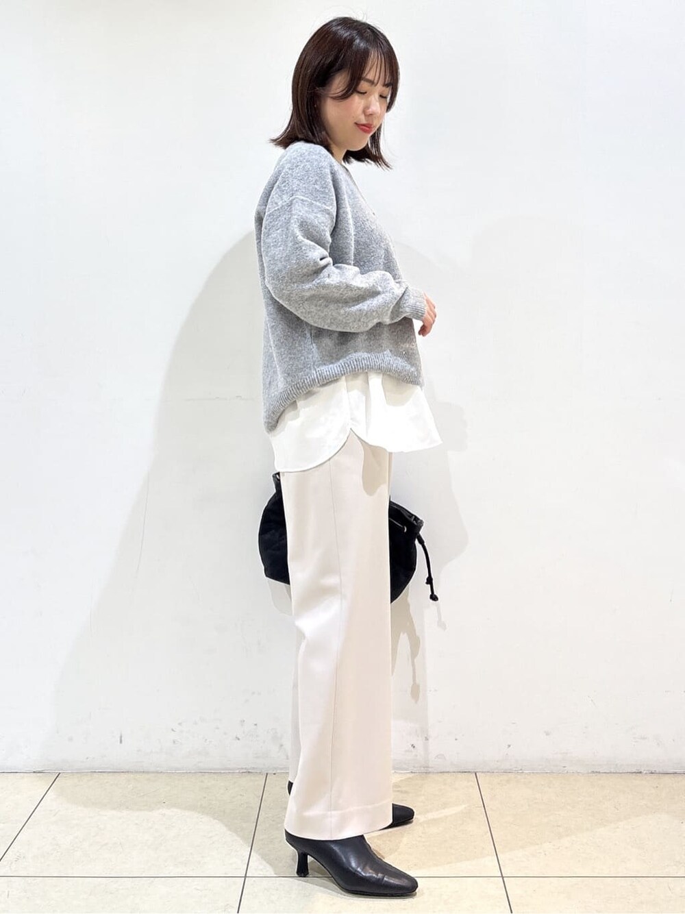 グレー系のニット/セーター、ホワイト系のTシャツ/カットソー、ベージュ系のその他パンツを着用したレディースの冬コーディネートの5枚目の写真