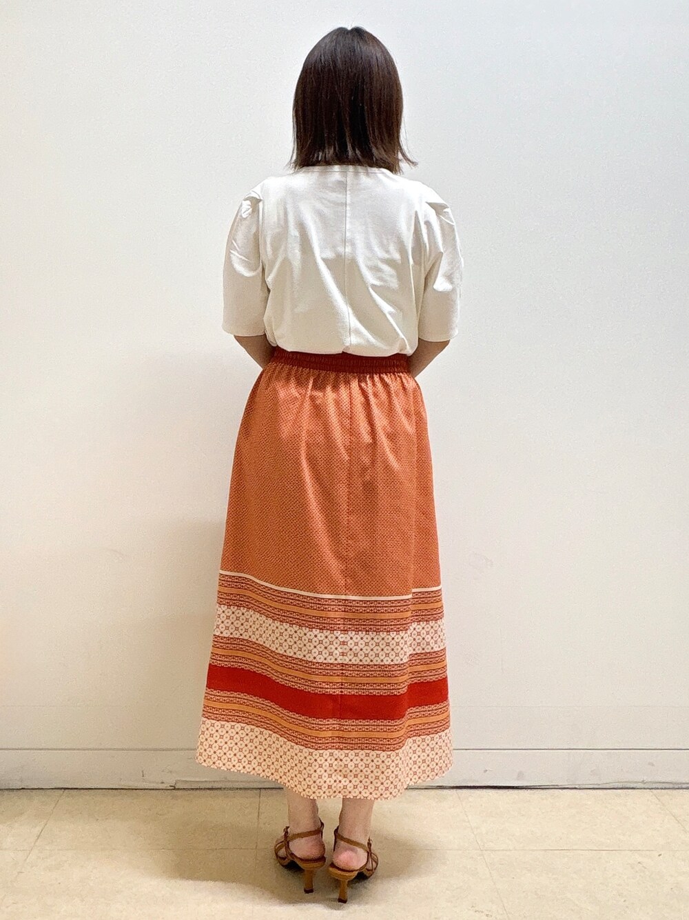 ホワイト系のTシャツ/カットソー、オレンジ系のスカート、オレンジ系のショルダーバッグを着用したレディースの夏コーディネートの6枚目の写真