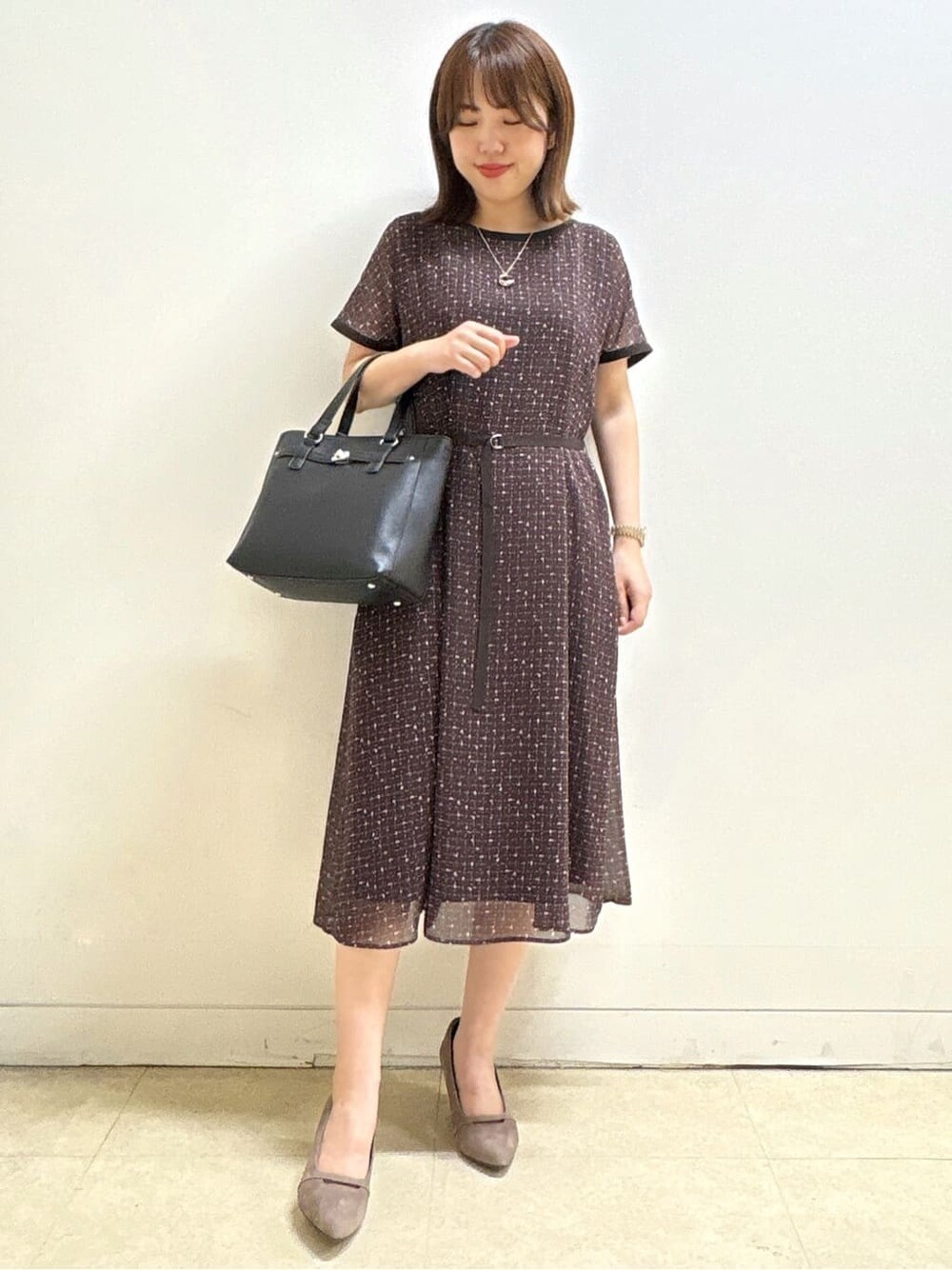 ブラウン系のワンピース、ベージュ系のパンプス、ブラック系のハンドバッグを着用したレディースの秋コーディネートの4枚目の写真