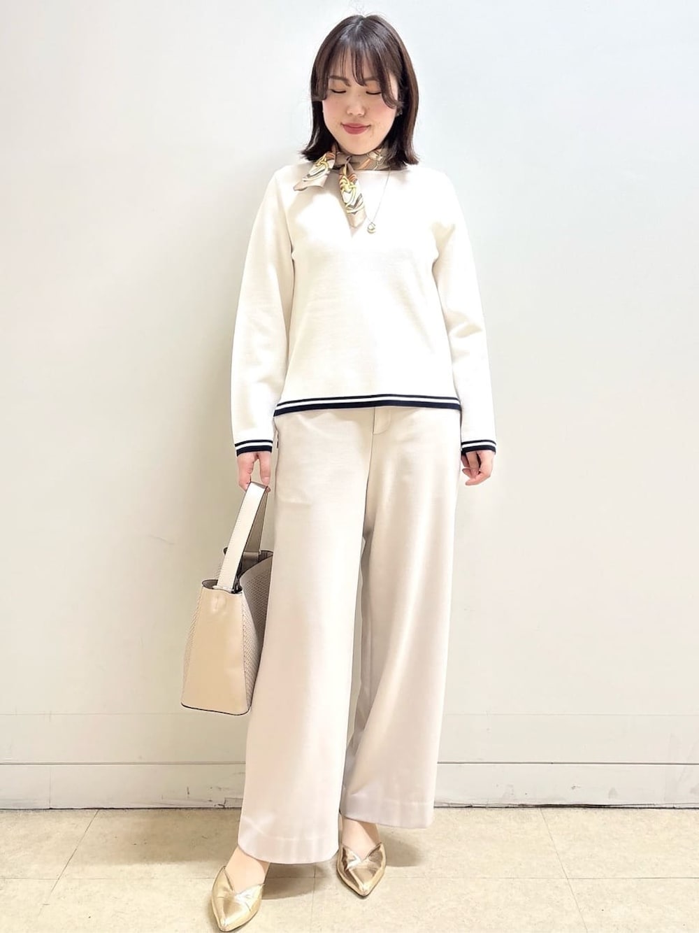 ベージュ系のその他パンツ、ホワイト系のニット/セーター、オレンジ系のカーディガン/ボレロを着用したレディースの冬コーディネートの2枚目の写真