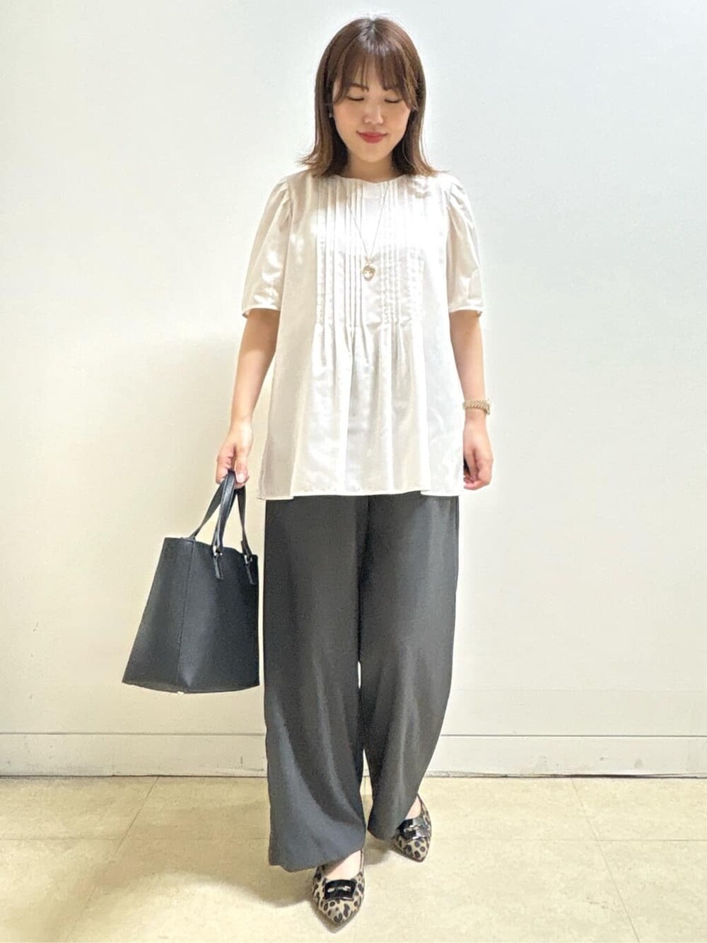 ベージュ系のシャツ/ブラウス、ベージュ系のパンプス、ブラック系のハンドバッグを着用したレディースの秋コーディネートの3枚目の写真