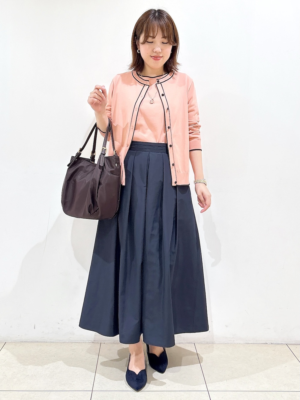 ピンク系のニット/セーター、ブルー系のスカート、ブルー系のパンプスを着用したレディースの秋コーディネートの7枚目の写真