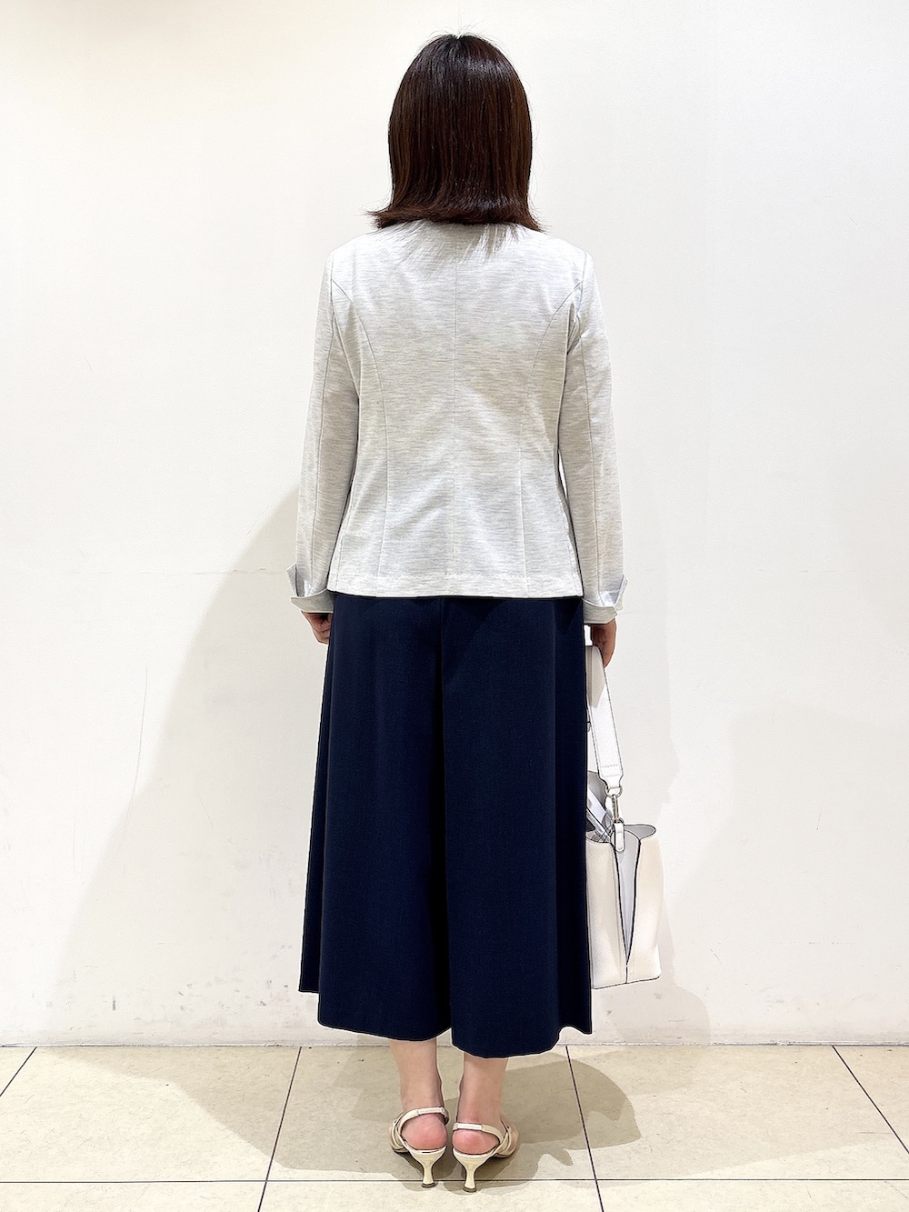 グレー系のノーカラージャケット、ホワイト系のトートバッグ、ブルー系のその他パンツを着用したレディースの春コーディネートの6枚目の写真