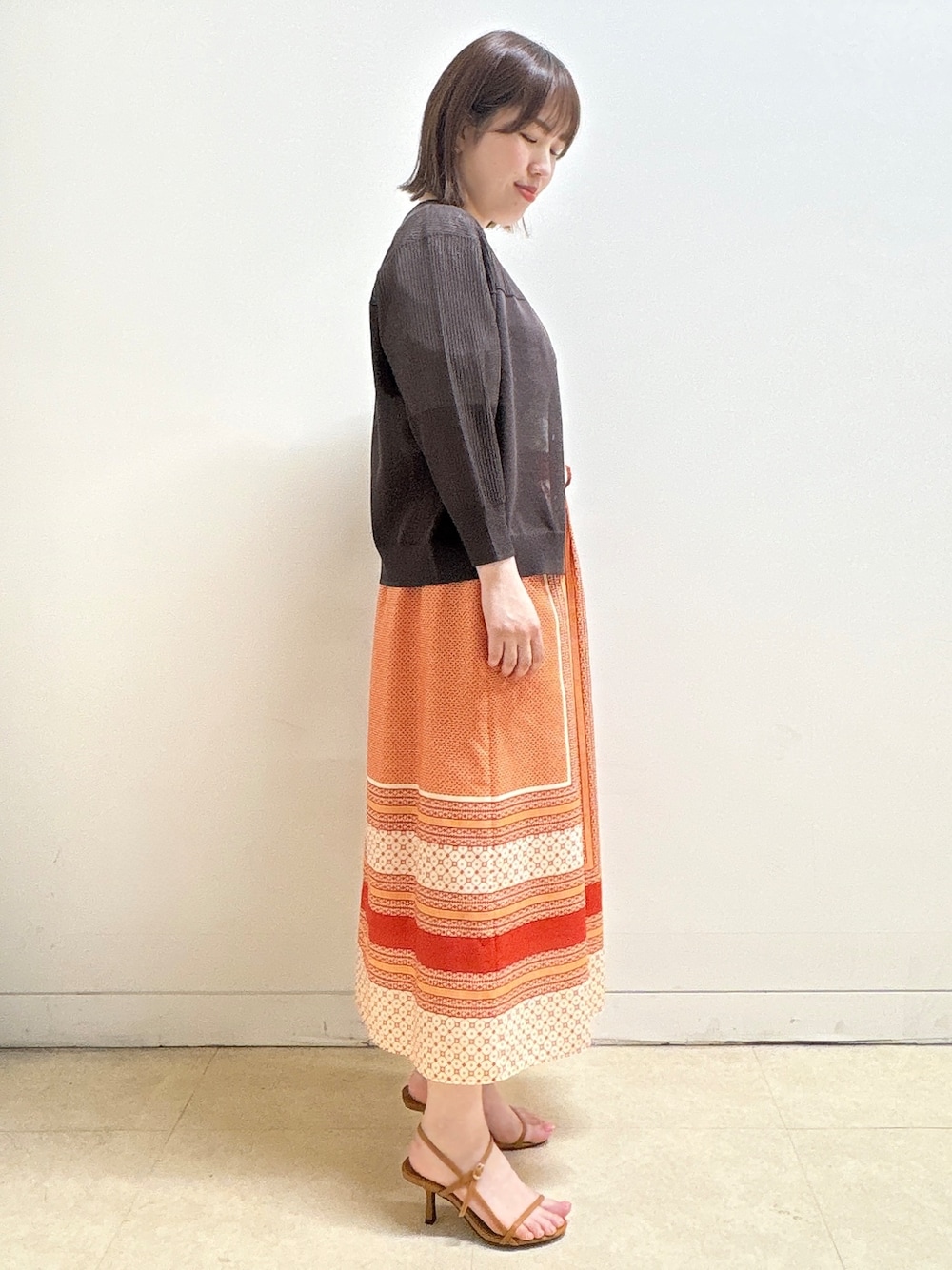 ブラウン系のカーディガン/ボレロ、ホワイト系のTシャツ/カットソー、オレンジ系のスカートを着用したレディースの夏コーディネートの5枚目の写真