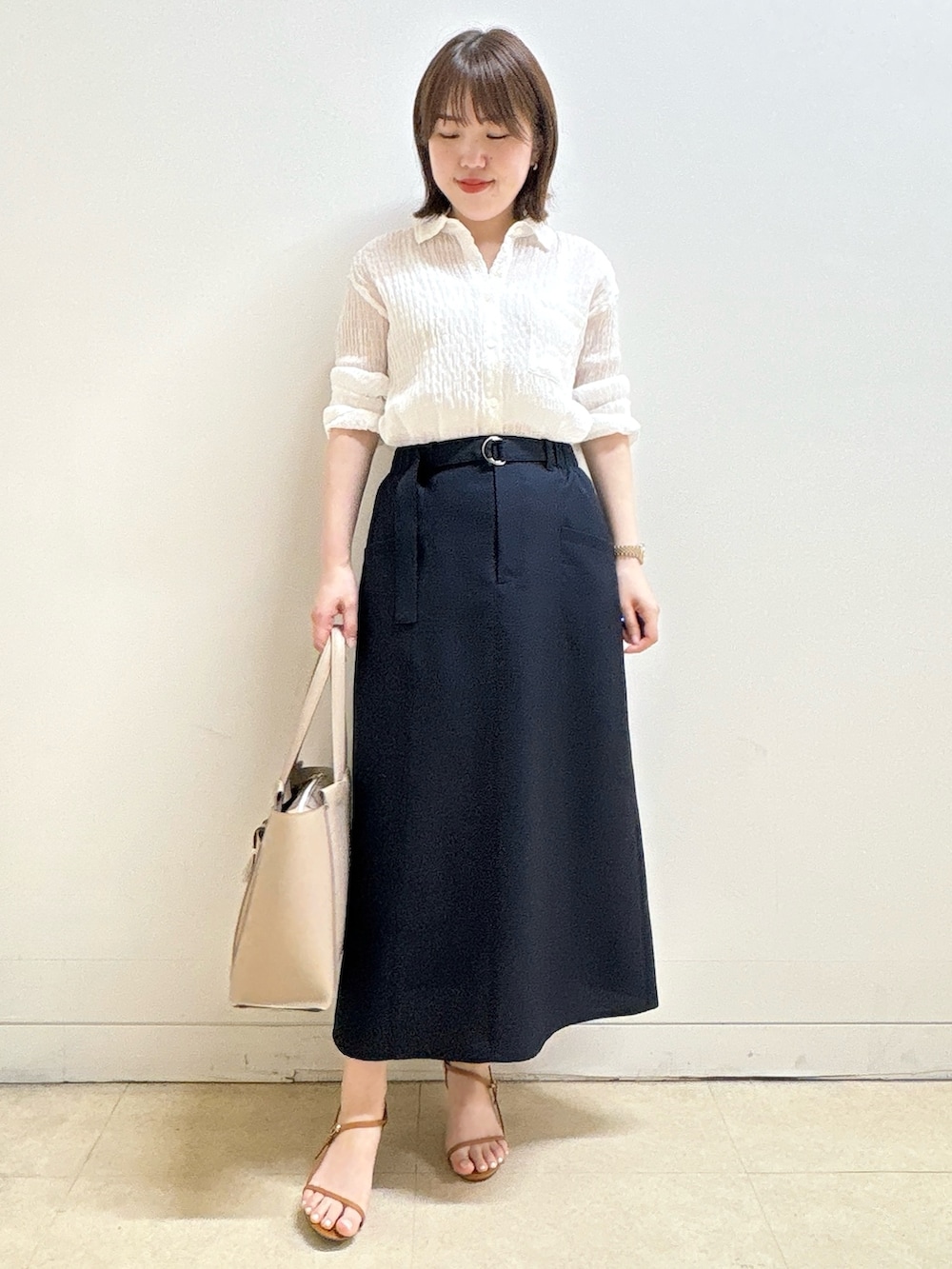 ホワイト系のシャツ/ブラウス、ブルー系のスカート、ベージュ系のトートバッグを着用したレディースの夏コーディネートの3枚目の写真