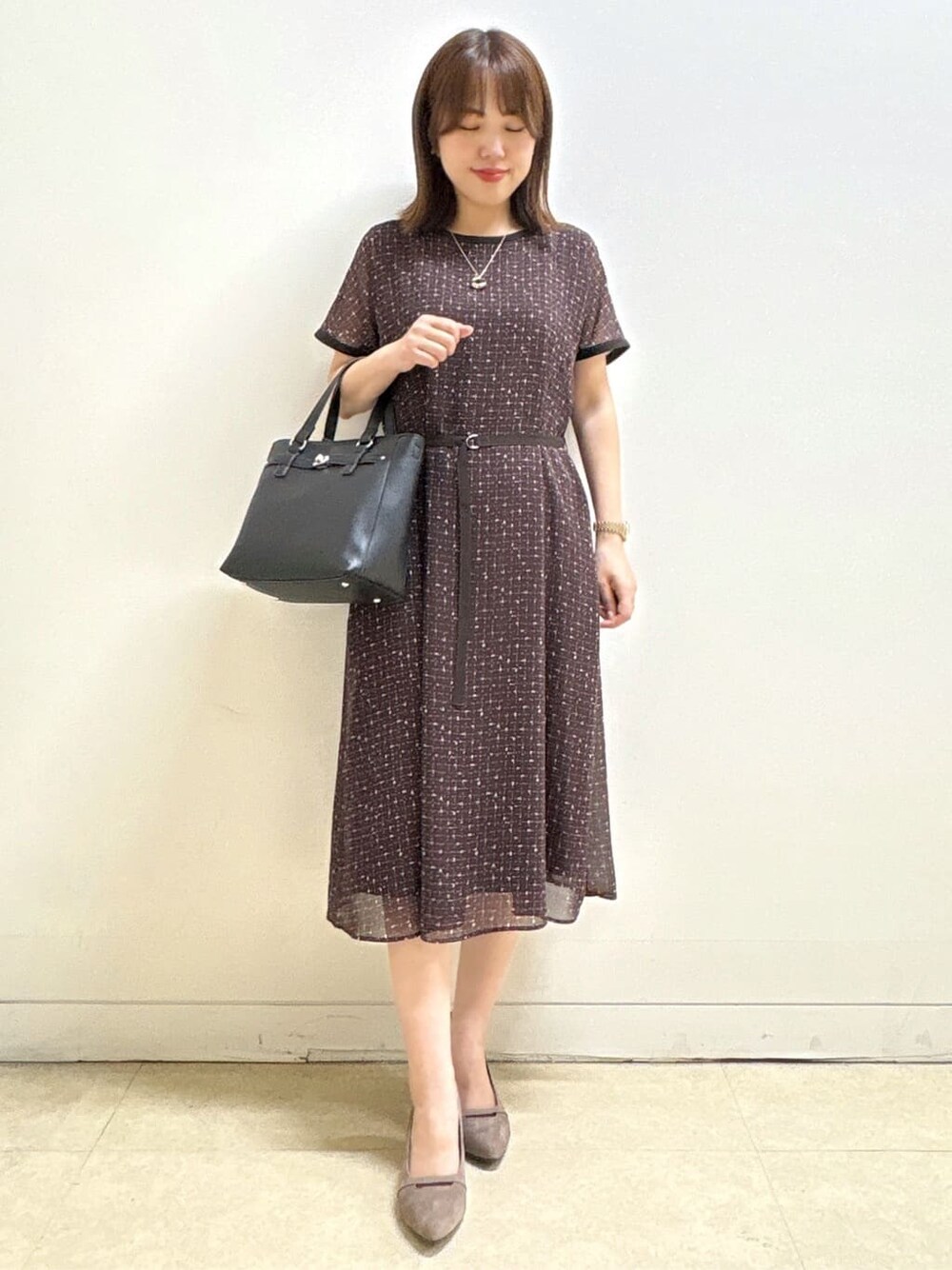 ブラウン系のワンピース、ベージュ系のパンプス、ブラック系のハンドバッグを着用したレディースの秋コーディネートの3枚目の写真