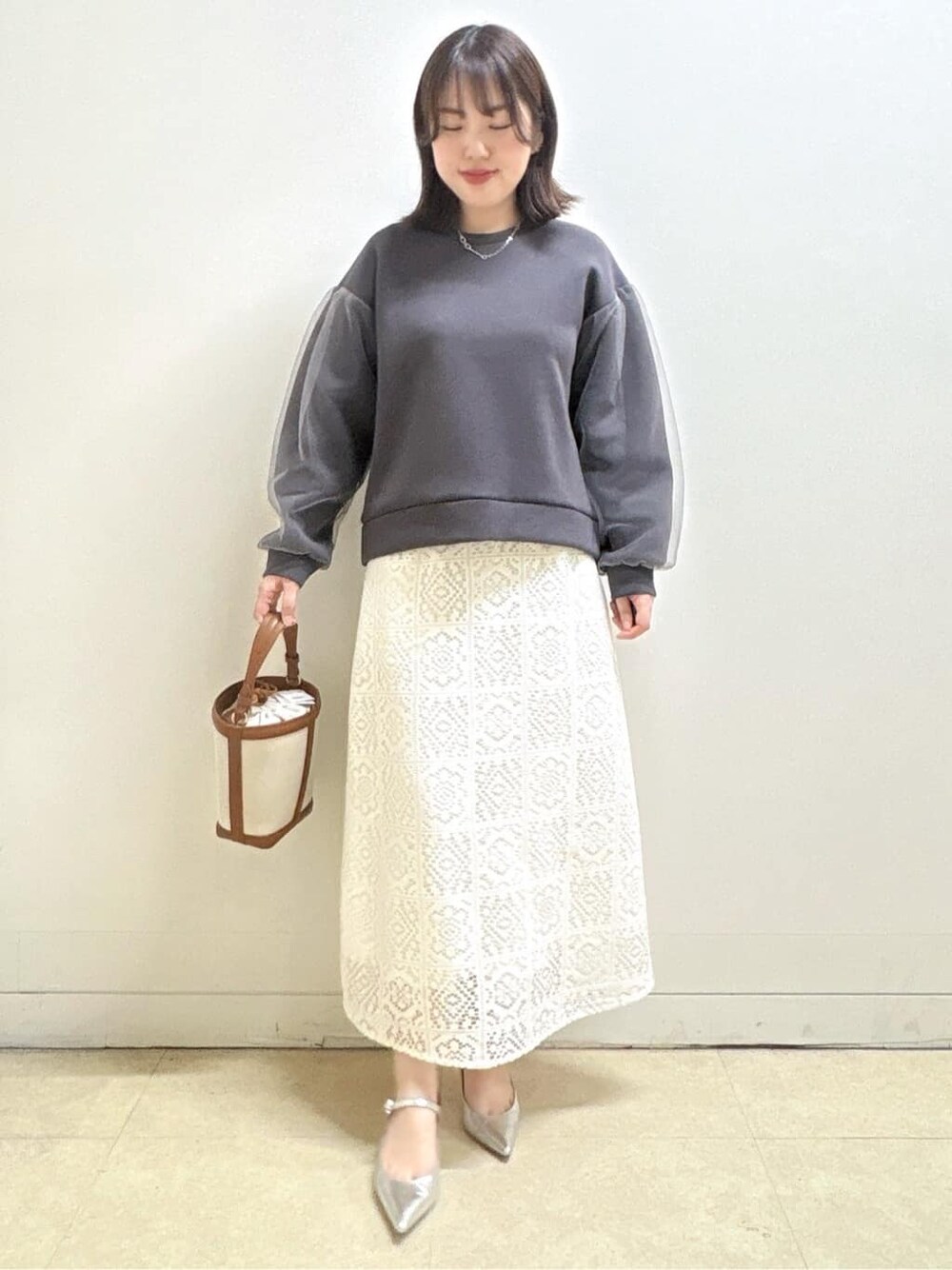 ホワイト系のスカート、グレー系のTシャツ/カットソー、イエロー系のショルダーバッグを着用したレディースの冬コーディネートの2枚目の写真