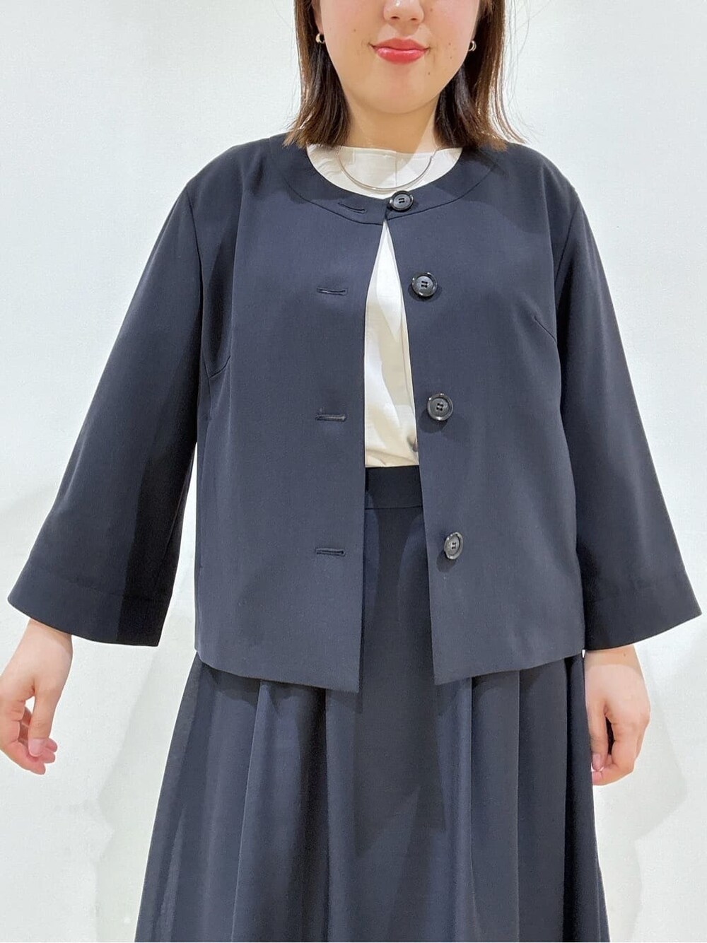 ブルー系のノーカラージャケット、ベージュ系のシャツ/ブラウス、ブルー系のスカートを着用したレディースの春コーディネートの10枚目の写真