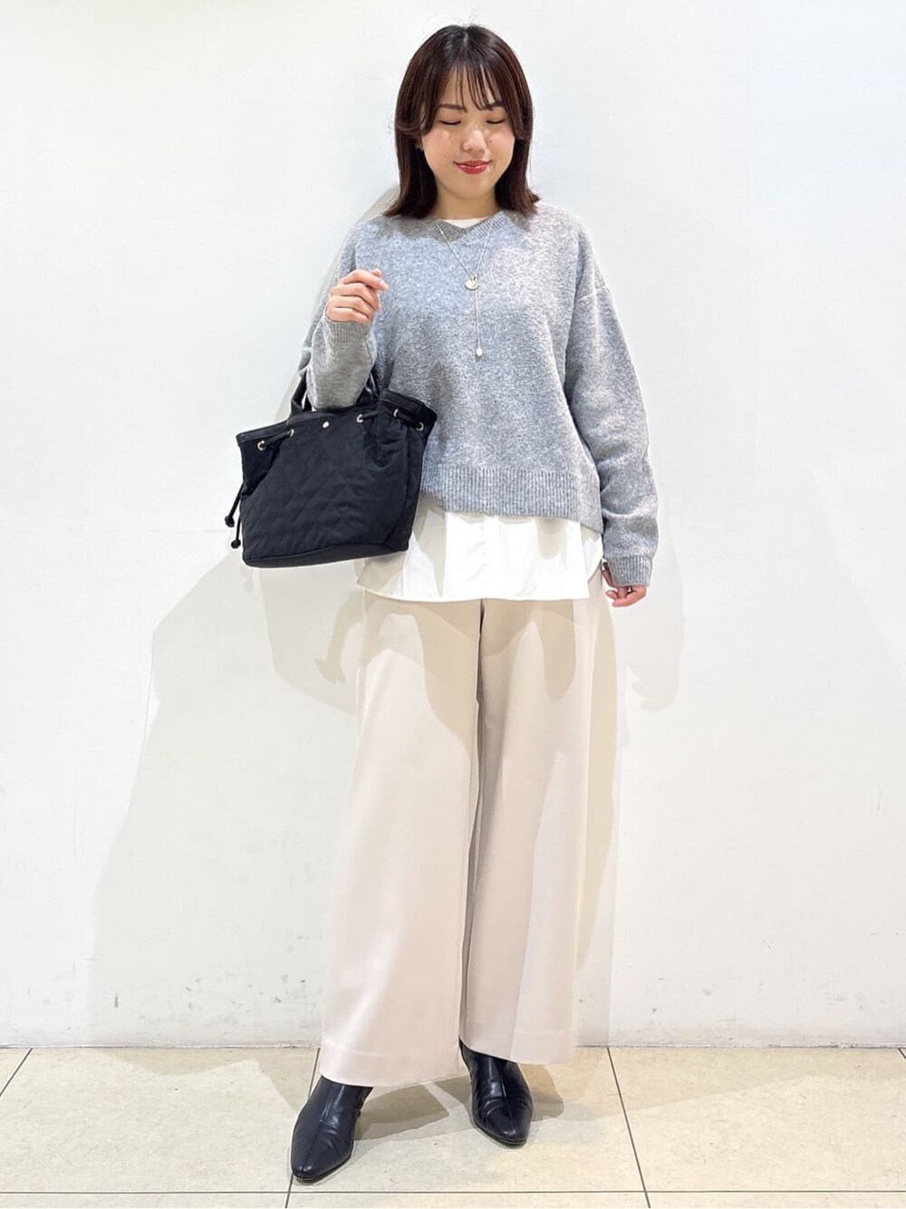 グレー系のニット/セーター、ホワイト系のTシャツ/カットソー、ベージュ系のその他パンツを着用したレディースの冬コーディネートの4枚目の写真