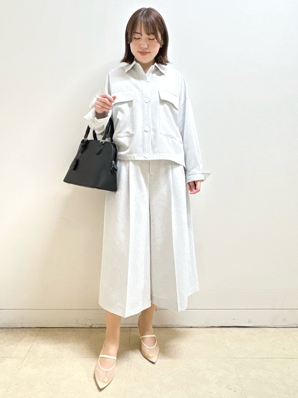 ブラック系のハンドバッグ、ホワイト系のTシャツ/カットソー、グレー系のブルゾンを着用したレディースの春コーディネートの3枚目の写真
