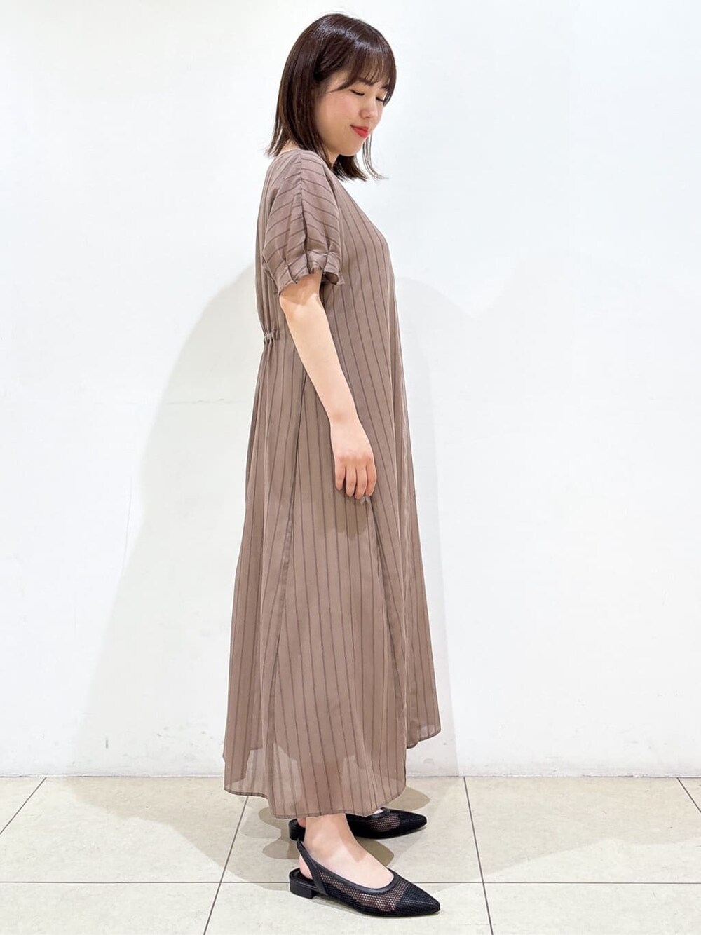 ブラウン系のワンピース、ブラック系のパンプス、ブラック系のハンドバッグを着用したレディースの夏コーディネートの6枚目の写真