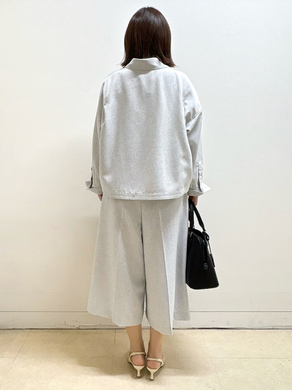 ブラック系のハンドバッグ、ホワイト系のTシャツ/カットソー、グレー系のブルゾンを着用したレディースの春コーディネートの6枚目の写真