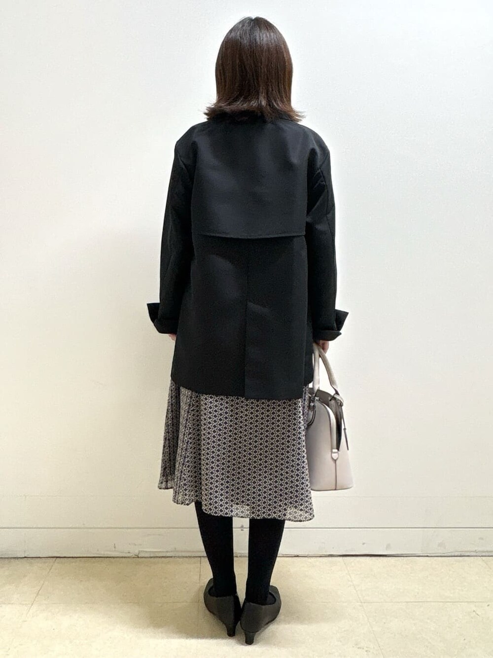 ブラック系のニット/セーター、ブルー系のスカート、ブラック系のパンプスを着用したレディースの冬コーディネートの9枚目の写真