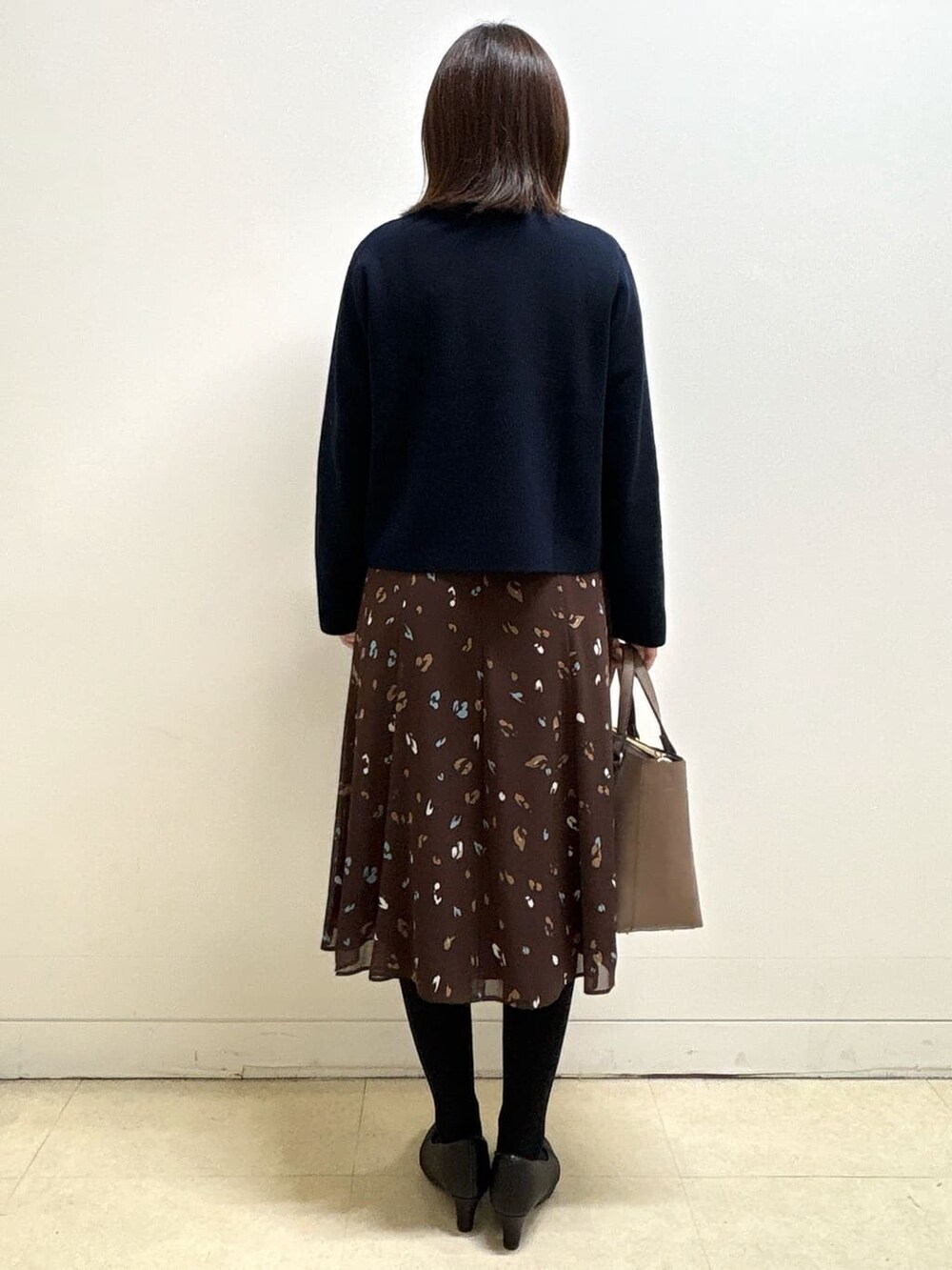 ブルー系のカーディガン/ボレロ、ブラウン系のワンピース、ブラック系のパンプスを着用したレディースの冬コーディネートの6枚目の写真