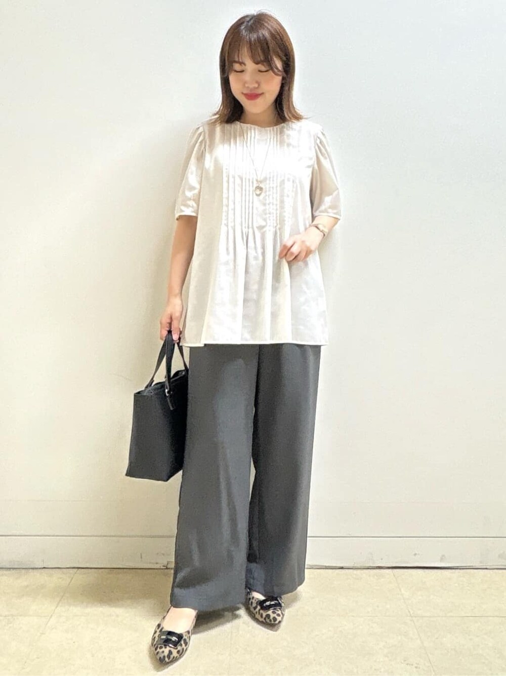 ベージュ系のシャツ/ブラウス、ベージュ系のパンプス、ブラック系のハンドバッグを着用したレディースの秋コーディネートの2枚目の写真