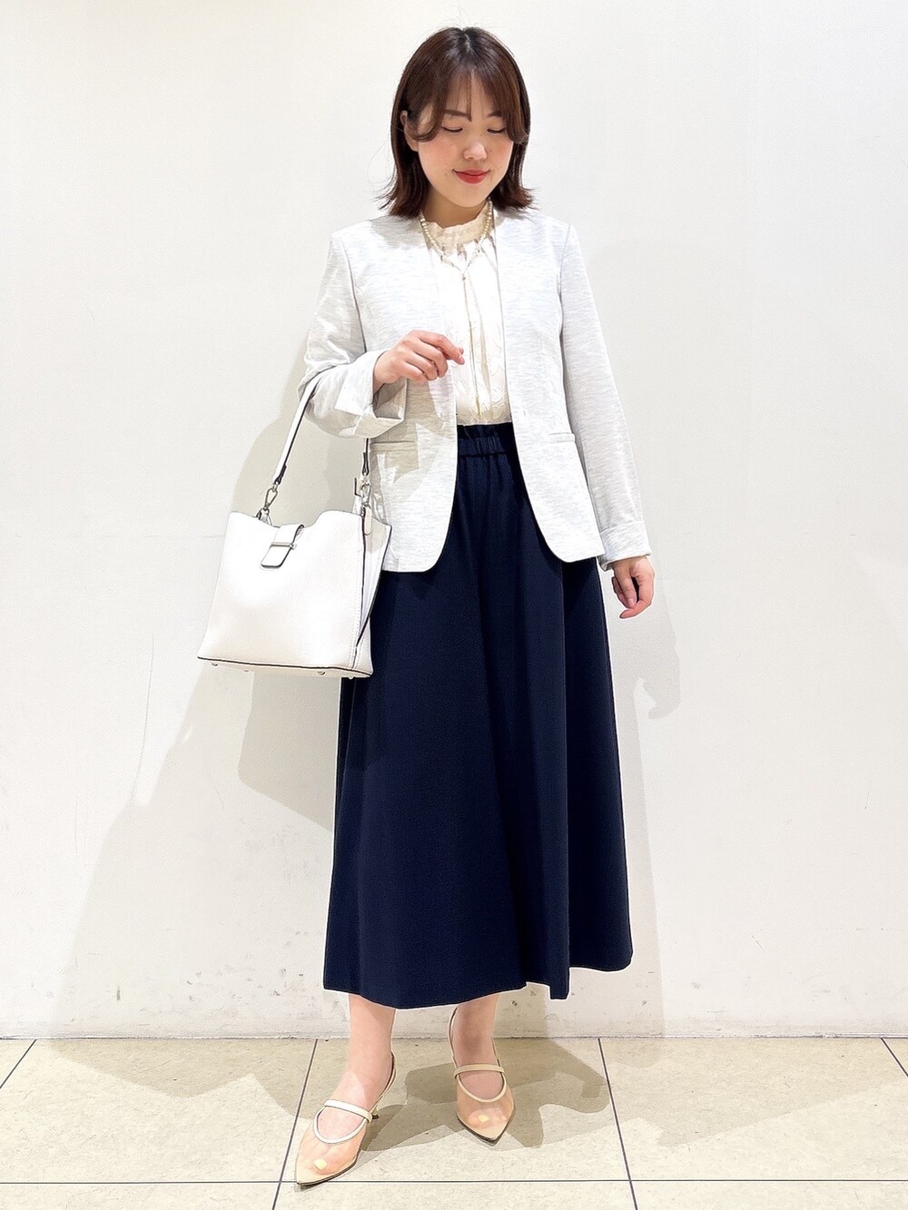 グレー系のノーカラージャケット、ホワイト系のトートバッグ、ブルー系のその他パンツを着用したレディースの春コーディネートの4枚目の写真