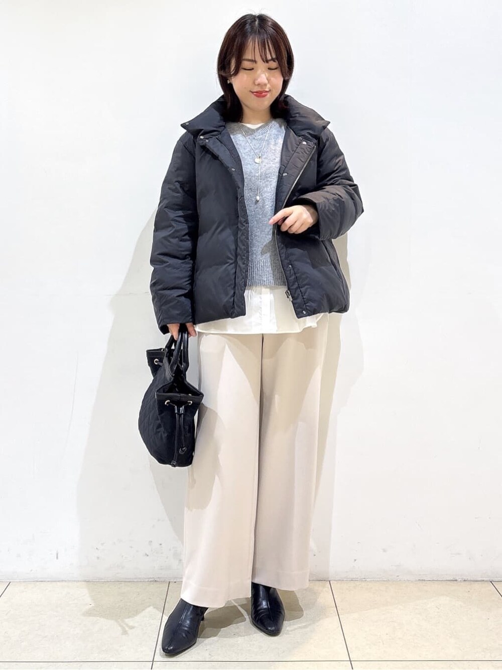 グレー系のニット/セーター、ホワイト系のTシャツ/カットソー、ベージュ系のその他パンツを着用したレディースの冬コーディネートの10枚目の写真