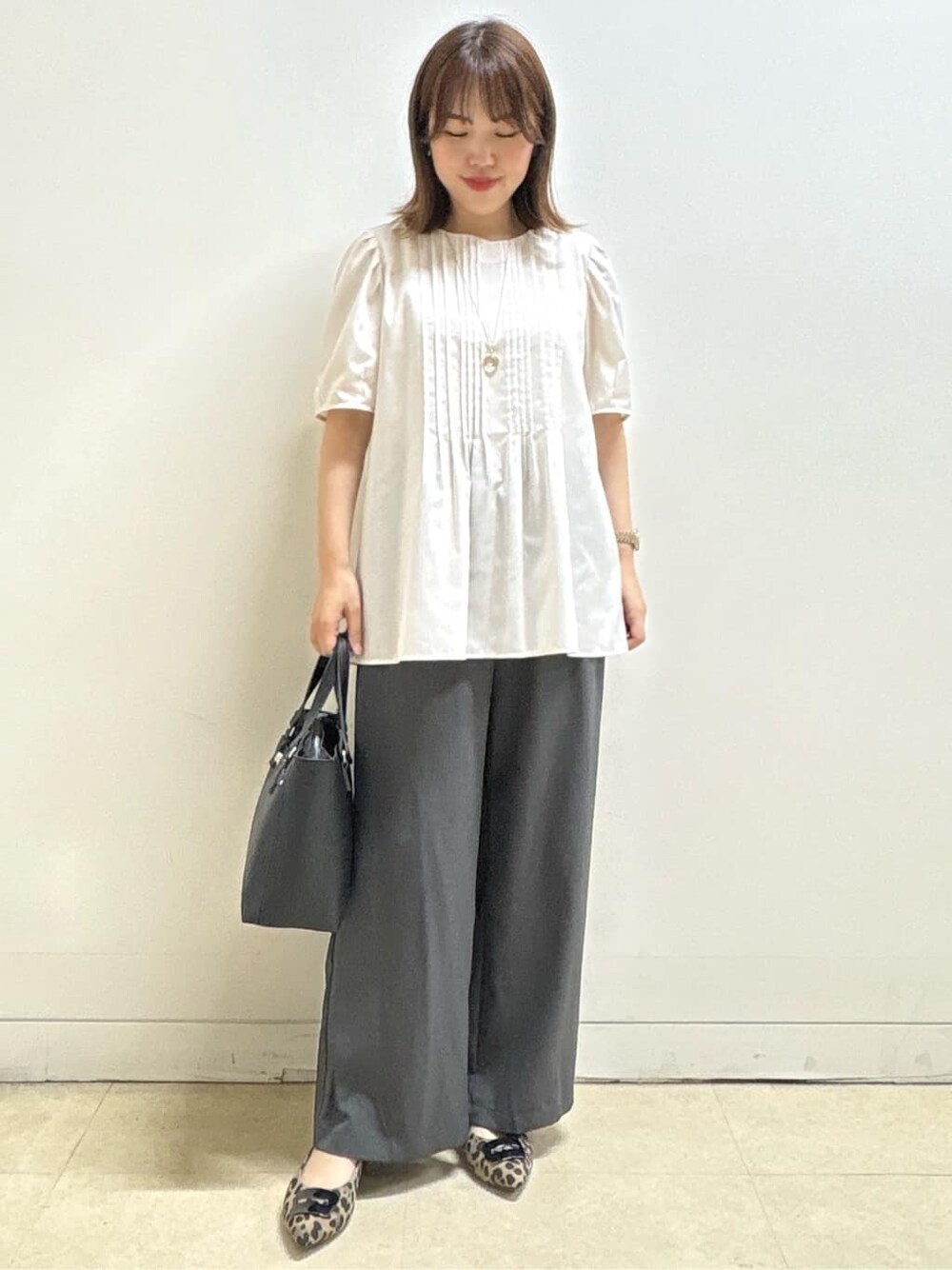 ベージュ系のシャツ/ブラウス、ベージュ系のパンプス、ブラック系のハンドバッグを着用したレディースの秋コーディネートの4枚目の写真