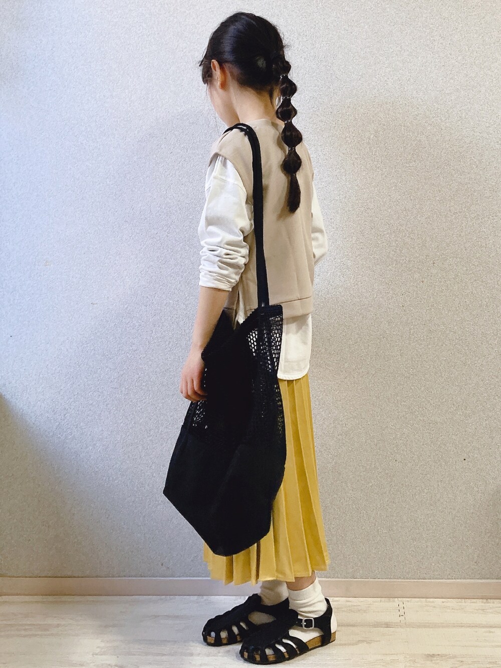 ホワイト系のTシャツ/カットソー、ベージュ系のベスト、イエロー系のスカートを着用したキッズの春コーディネートの2枚目の写真