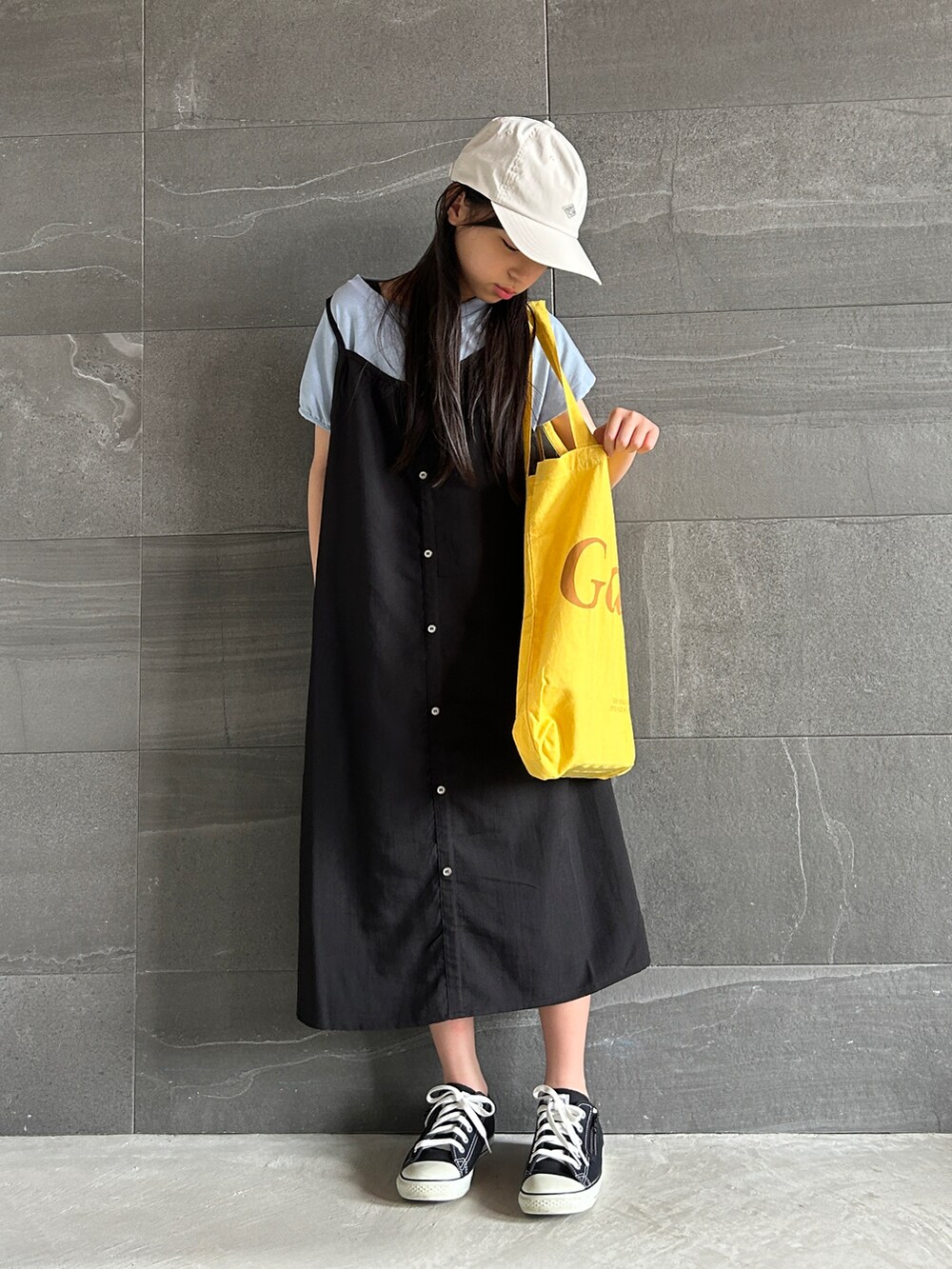 ブラック系のワンピース、イエロー系のトートバッグ、ブラック系のスニーカーを着用したキッズの夏コーディネートの2枚目の写真