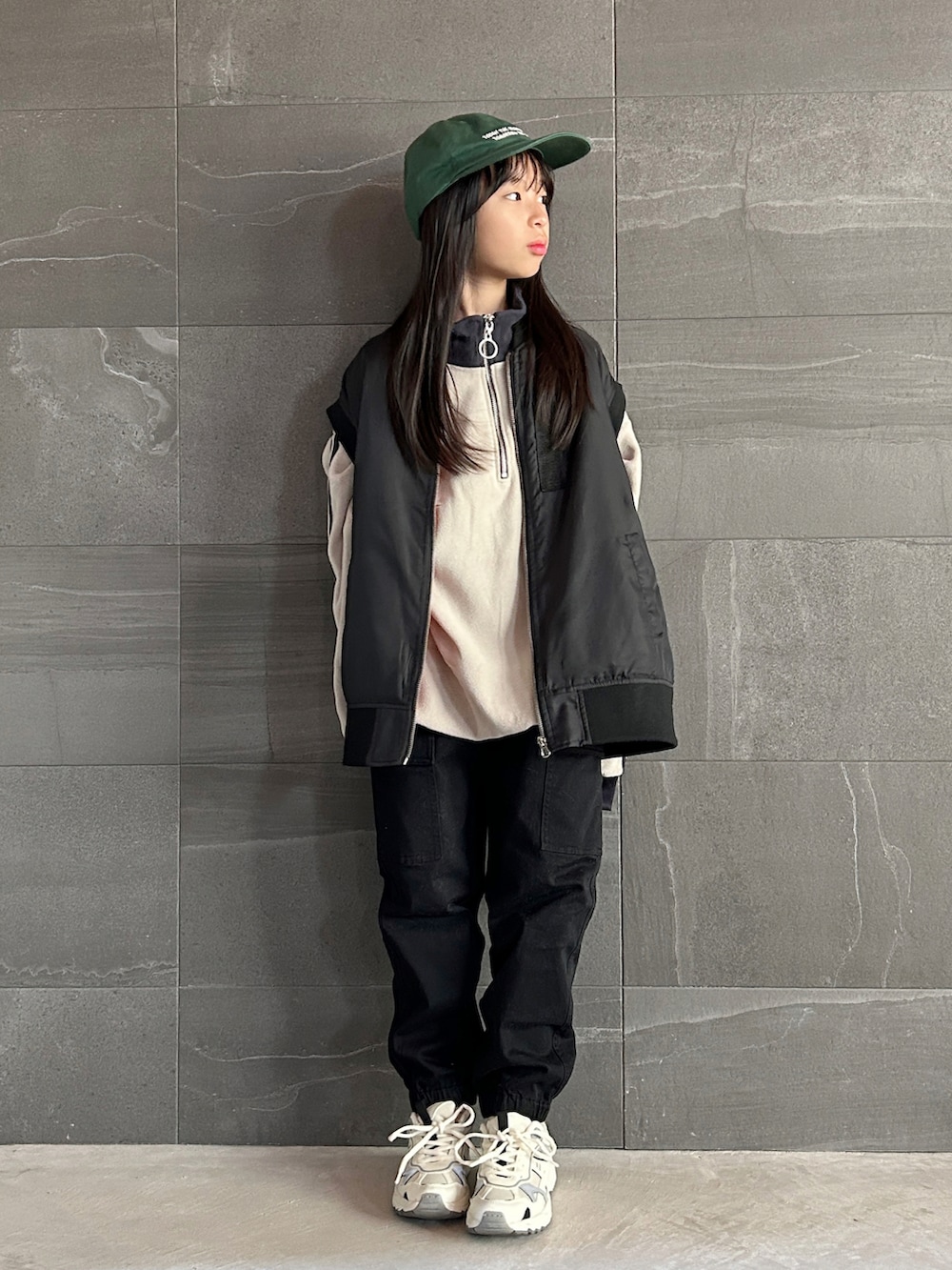 ブラック系のダウンベスト、グレー系のスウェット、ホワイト系のカーゴパンツを着用したキッズの秋コーディネートの2枚目の写真