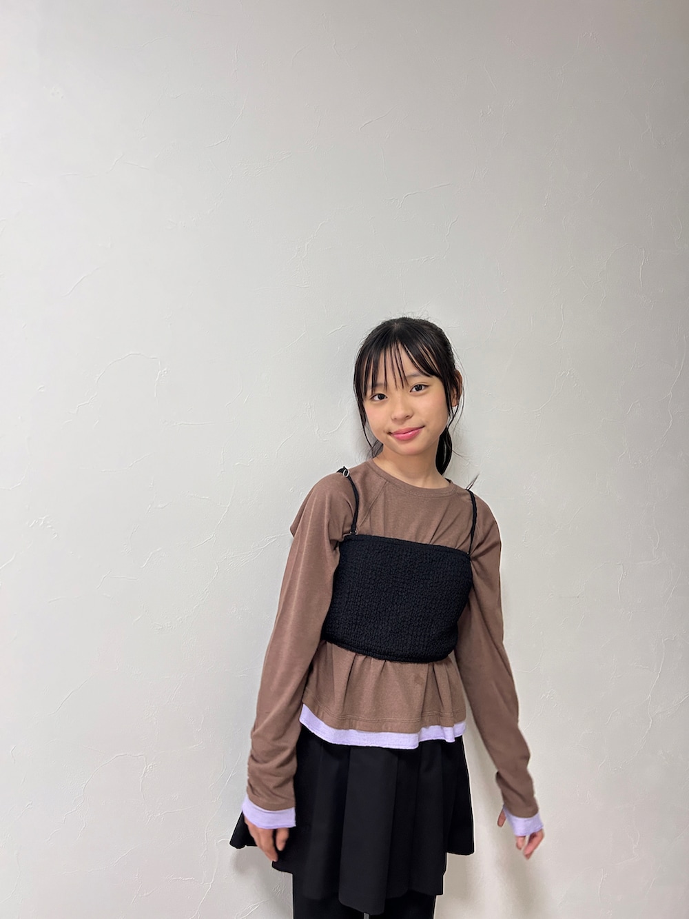ブラウン系のTシャツ/カットソー、ブラック系のスカート、ベージュ系のスニーカーを着用したキッズの秋コーディネートの5枚目の写真