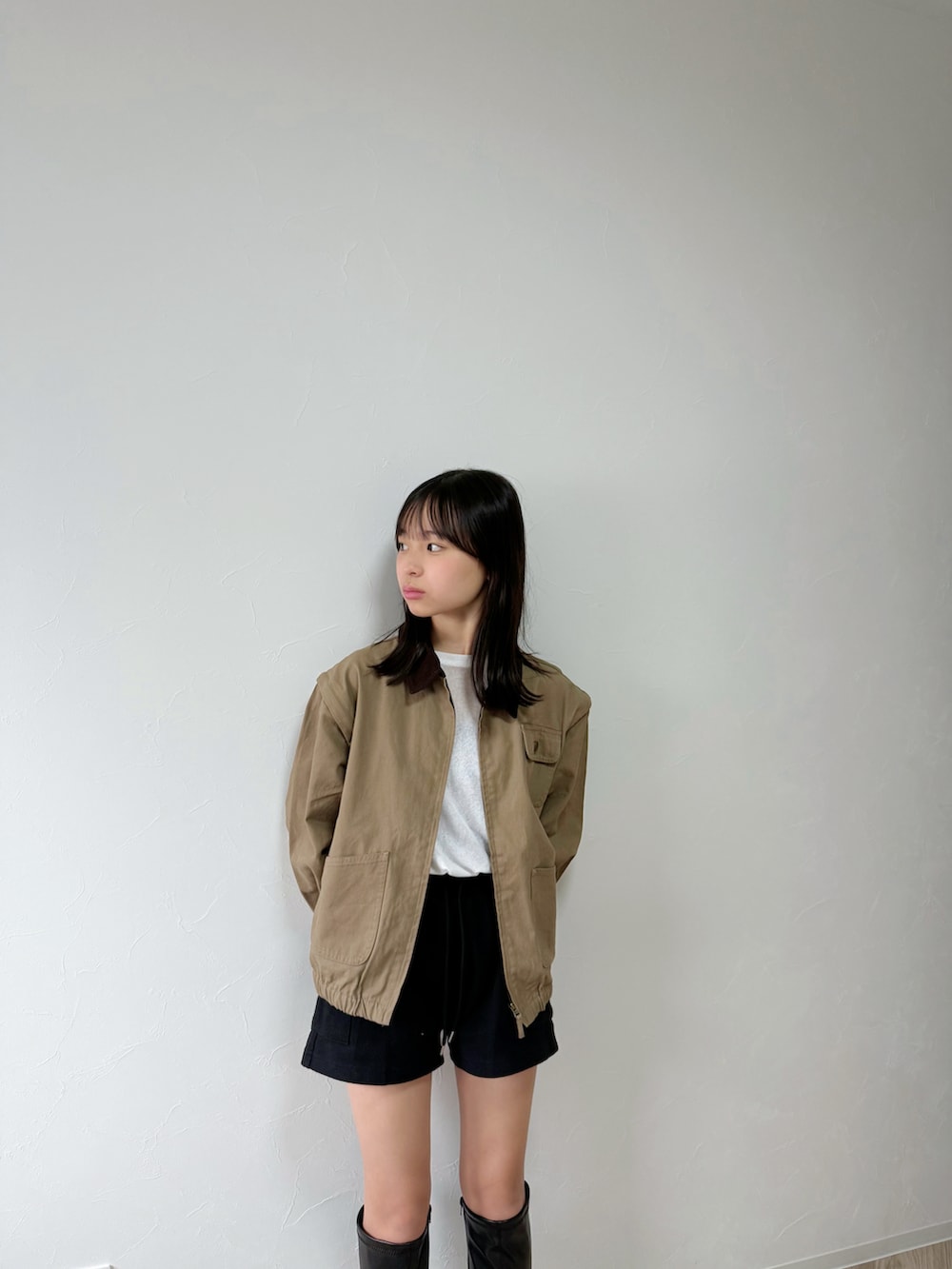 ホワイト系のTシャツ/カットソー、ベージュ系のブルゾン、ブラック系のブーツを着用したキッズの秋コーディネートの5枚目の写真