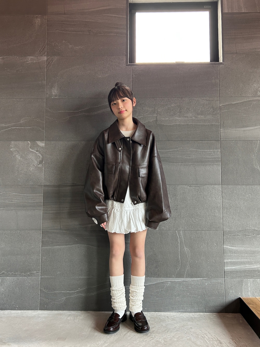 ブラウン系のブルゾン、ホワイト系のスカート、ベージュ系のTシャツ/カットソーを着用したキッズの冬コーディネートの3枚目の写真