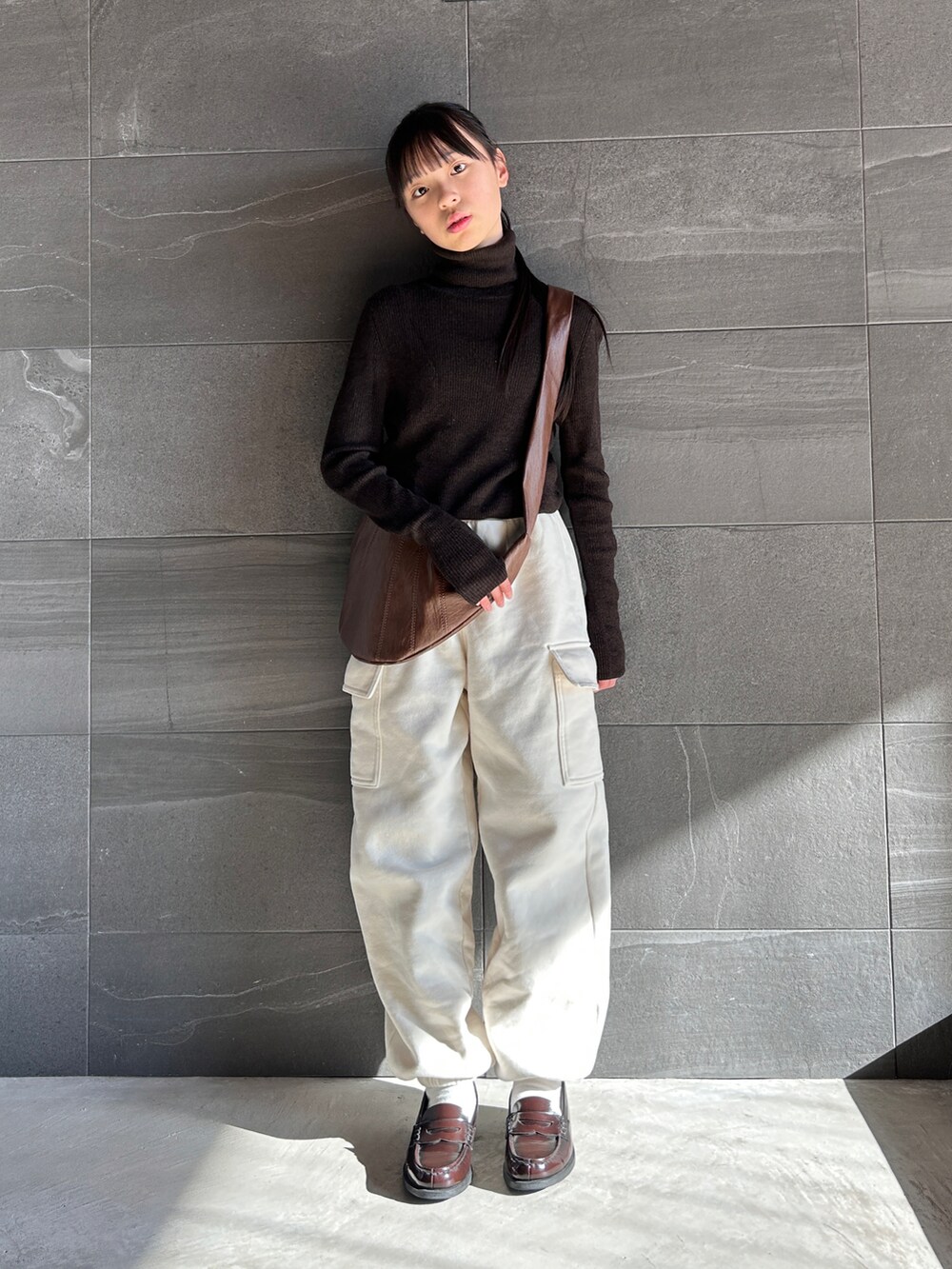 ブラウン系のニット/セーター、ホワイト系のスウェットパンツ、ブラウン系のショルダーバッグを着用したキッズの冬コーディネートの2枚目の写真