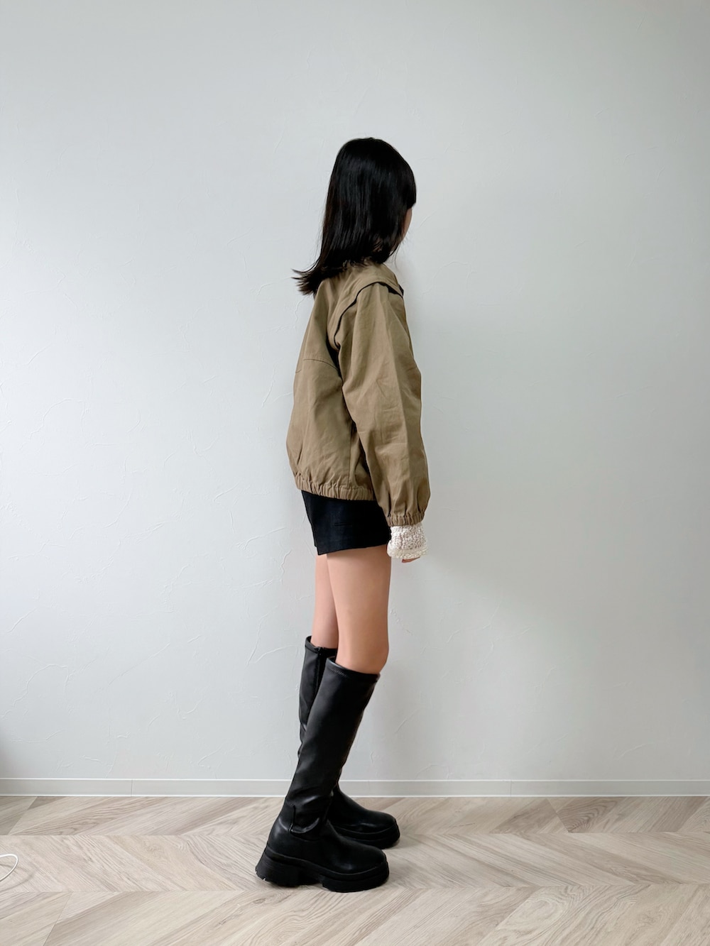 ホワイト系のTシャツ/カットソー、ベージュ系のブルゾン、ブラック系のブーツを着用したキッズの秋コーディネートの4枚目の写真